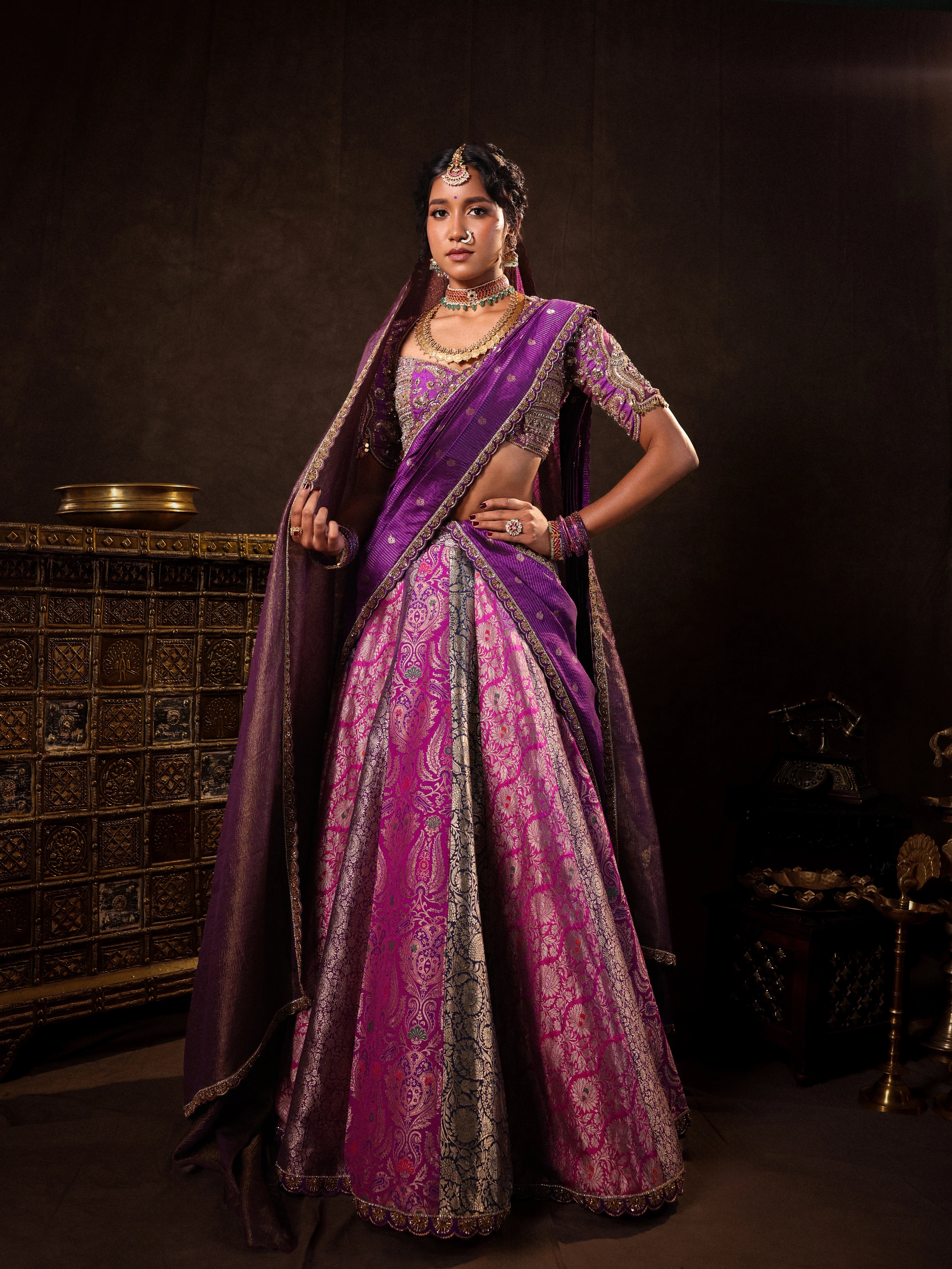 Model Gayathri Dhanasekar in a purple banarasi brocade silk half saree with glass bangles and NAC jewellery.
