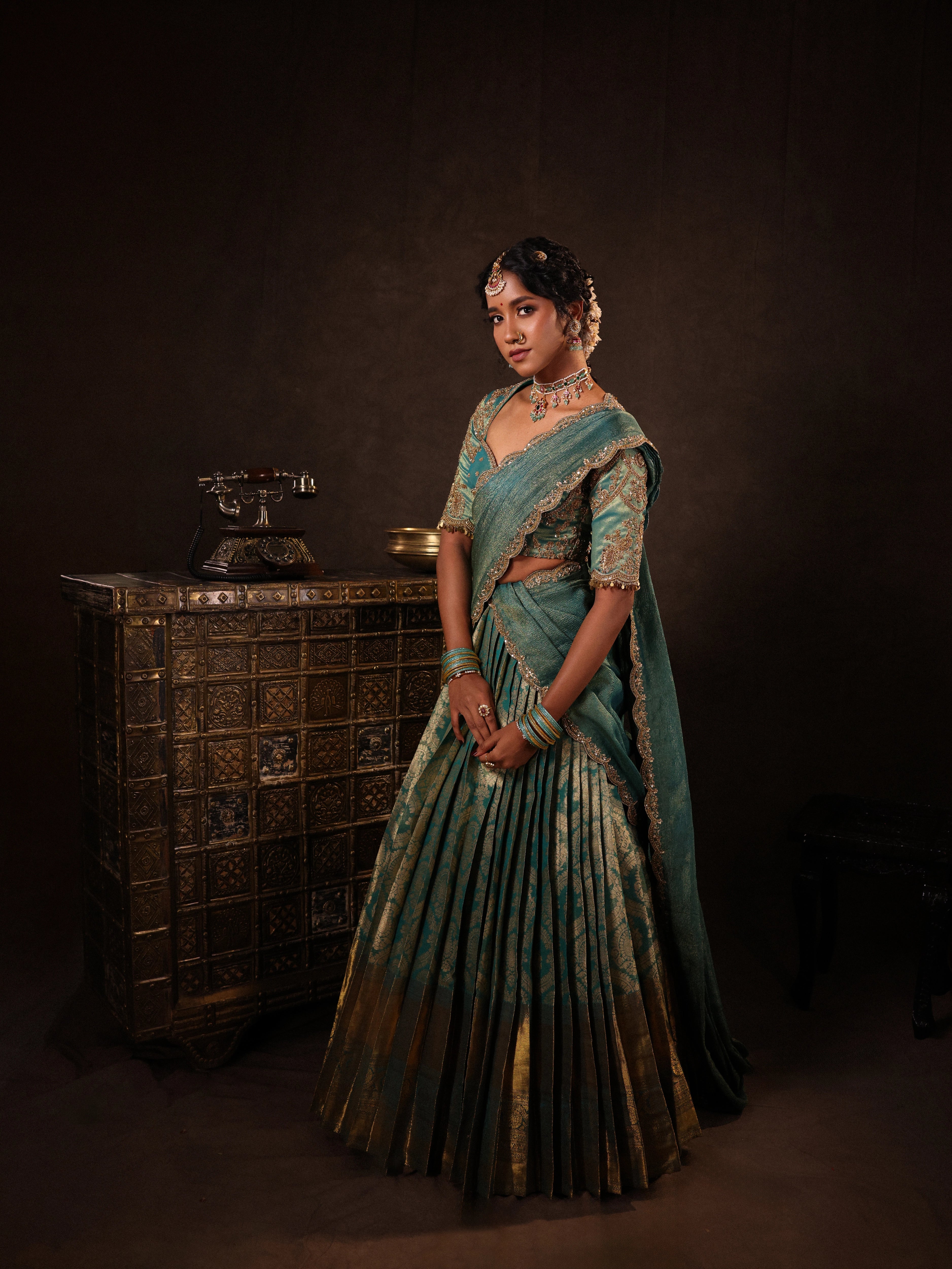 Model Gayathri Dhanasekar in teal jacquard silk half saree with glass bangles and NAC jewellery.