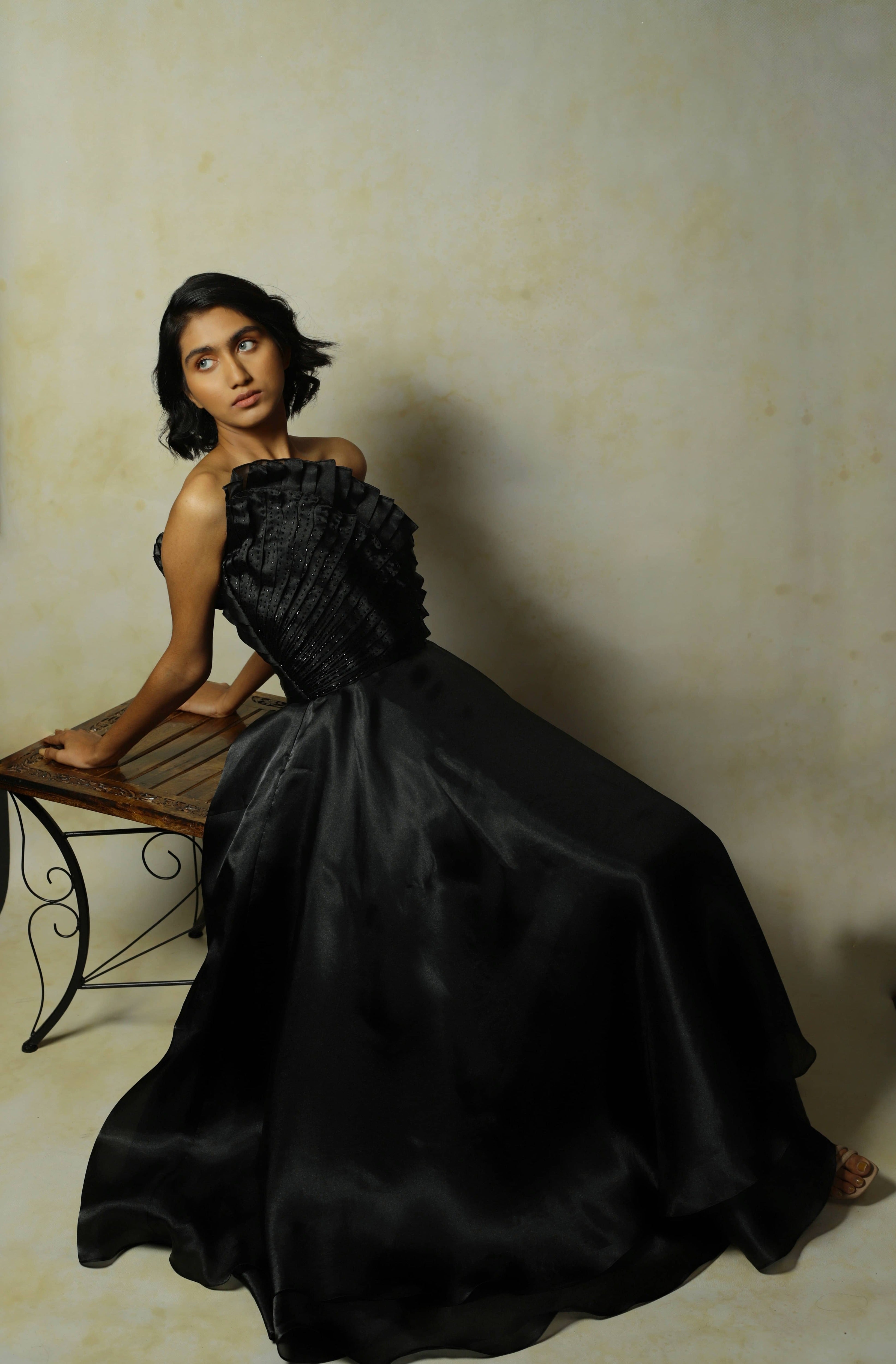 model posing in black tissue organza with structured upper body looking to her right. almost contortonist pose