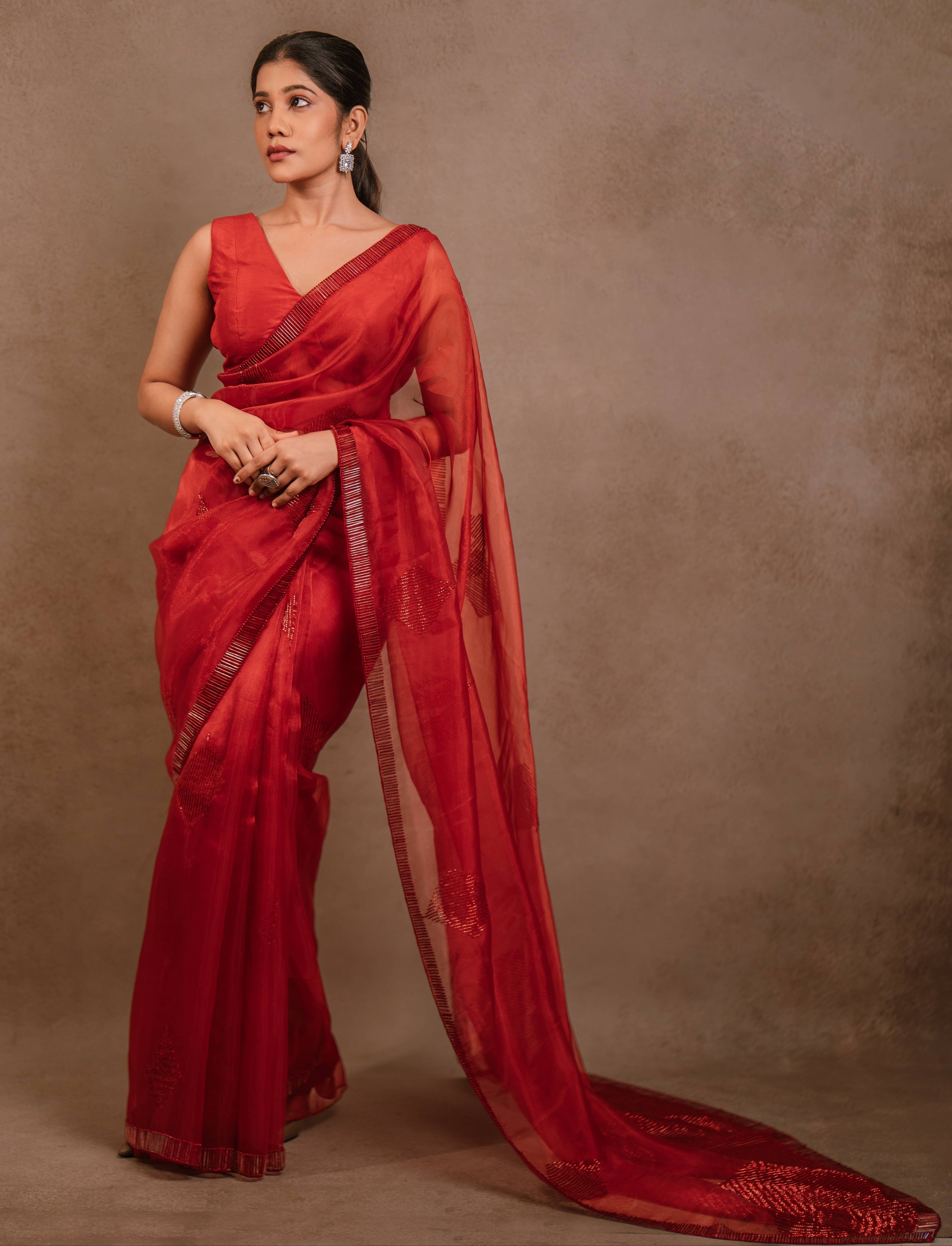 posing for full design in a red-orange organza saree intricately handcrafted with cutdana lines, designed by team Archana Karthick.
