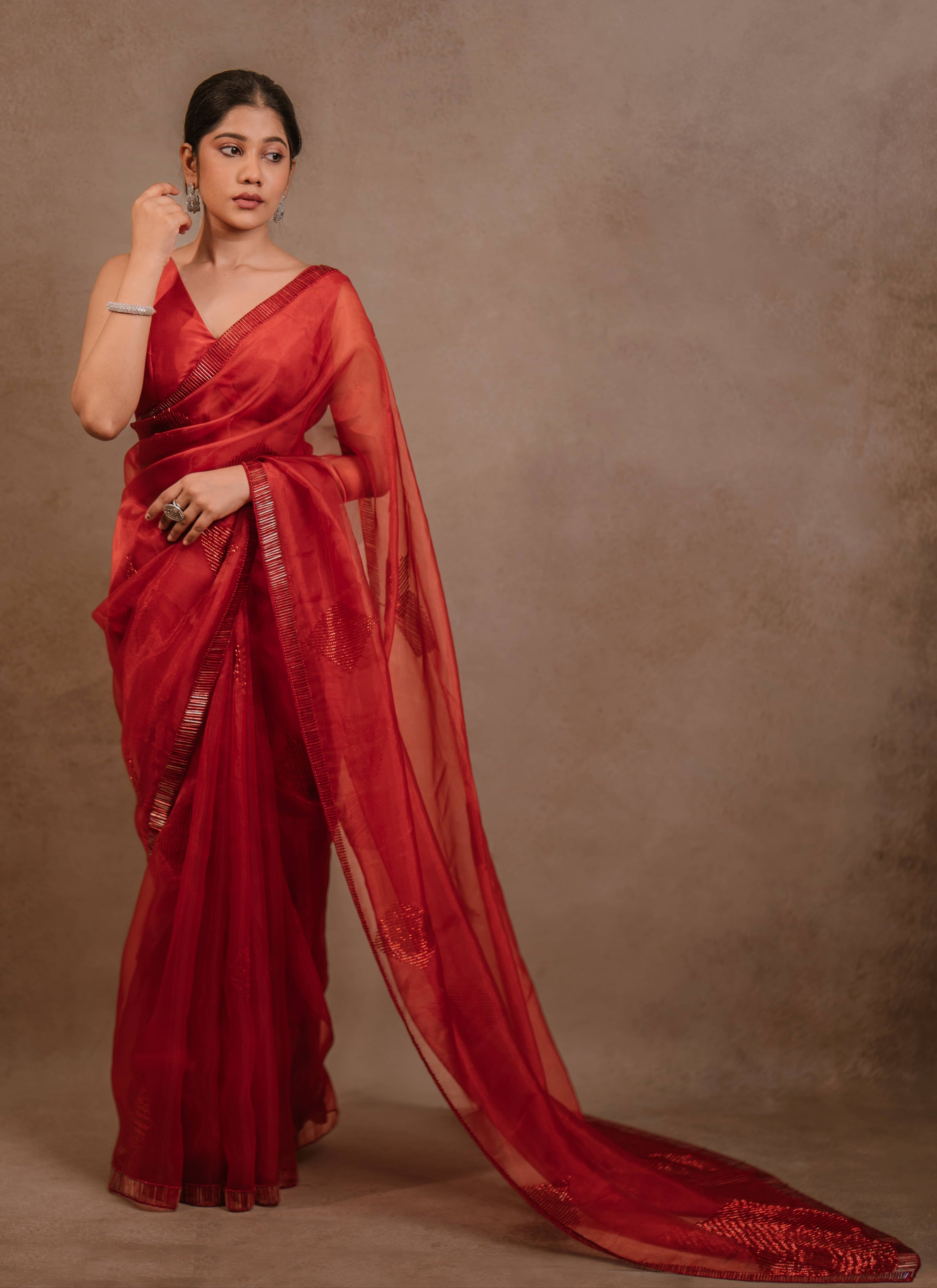 showcasing full design in a red-orange organza saree intricately handcrafted with cutdana lines, designed by team Archana Karthick.