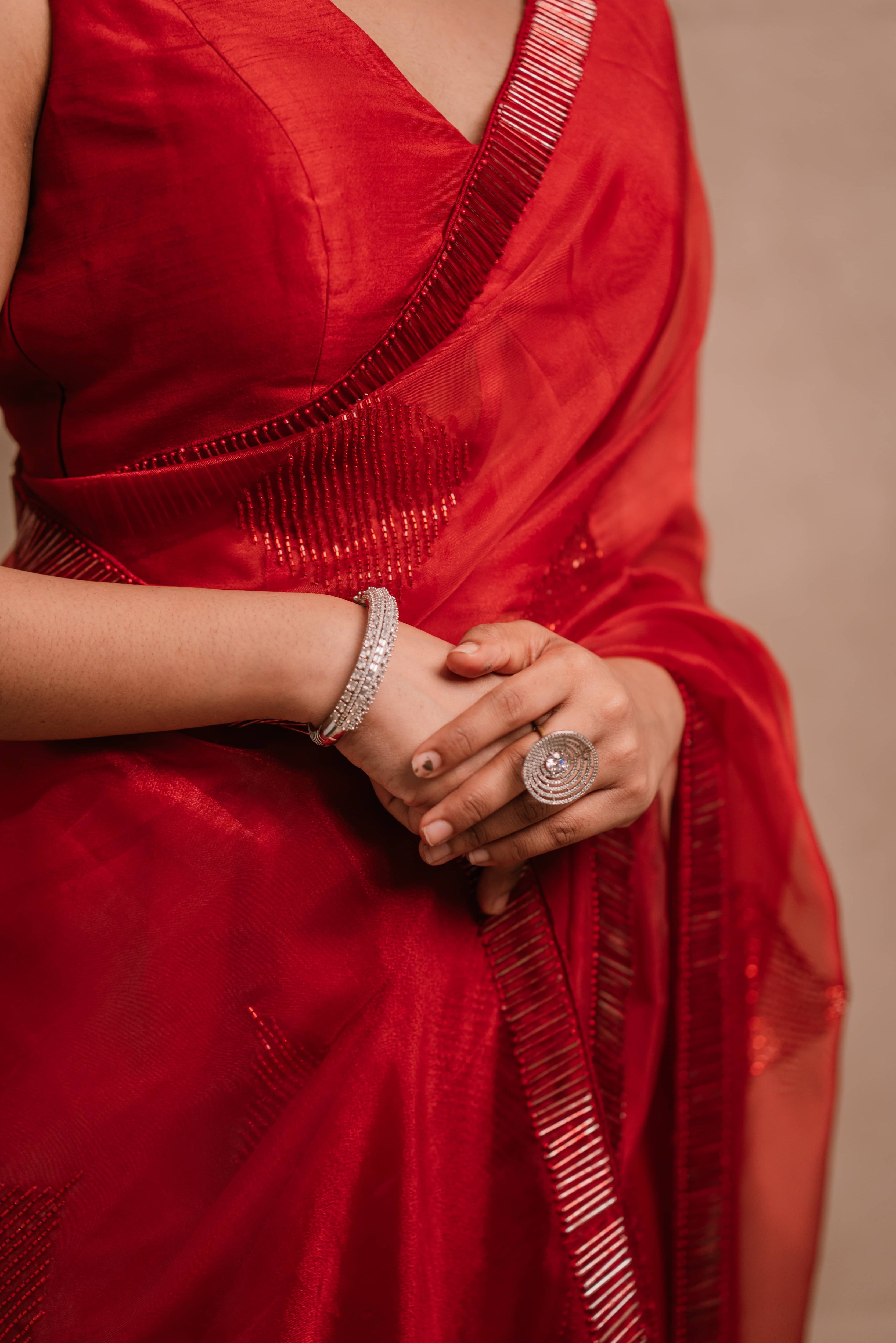 showcasing side in a red-orange organza saree intricately handcrafted with cutdana lines, designed by team Archana Karthick.