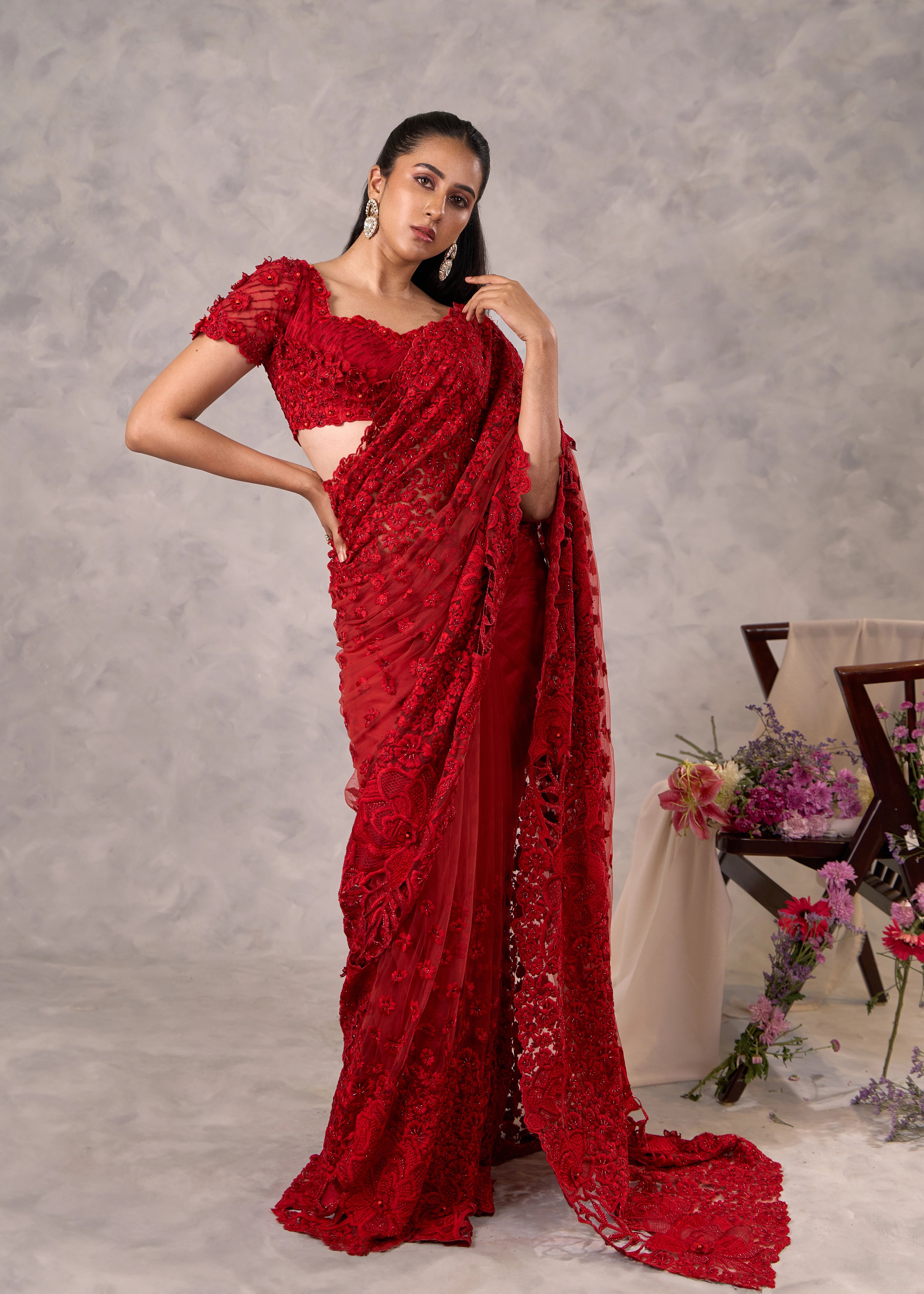 Actress Akshaya Hariharan in red net saree with french knot floral motifs. Bridal & festive wear.