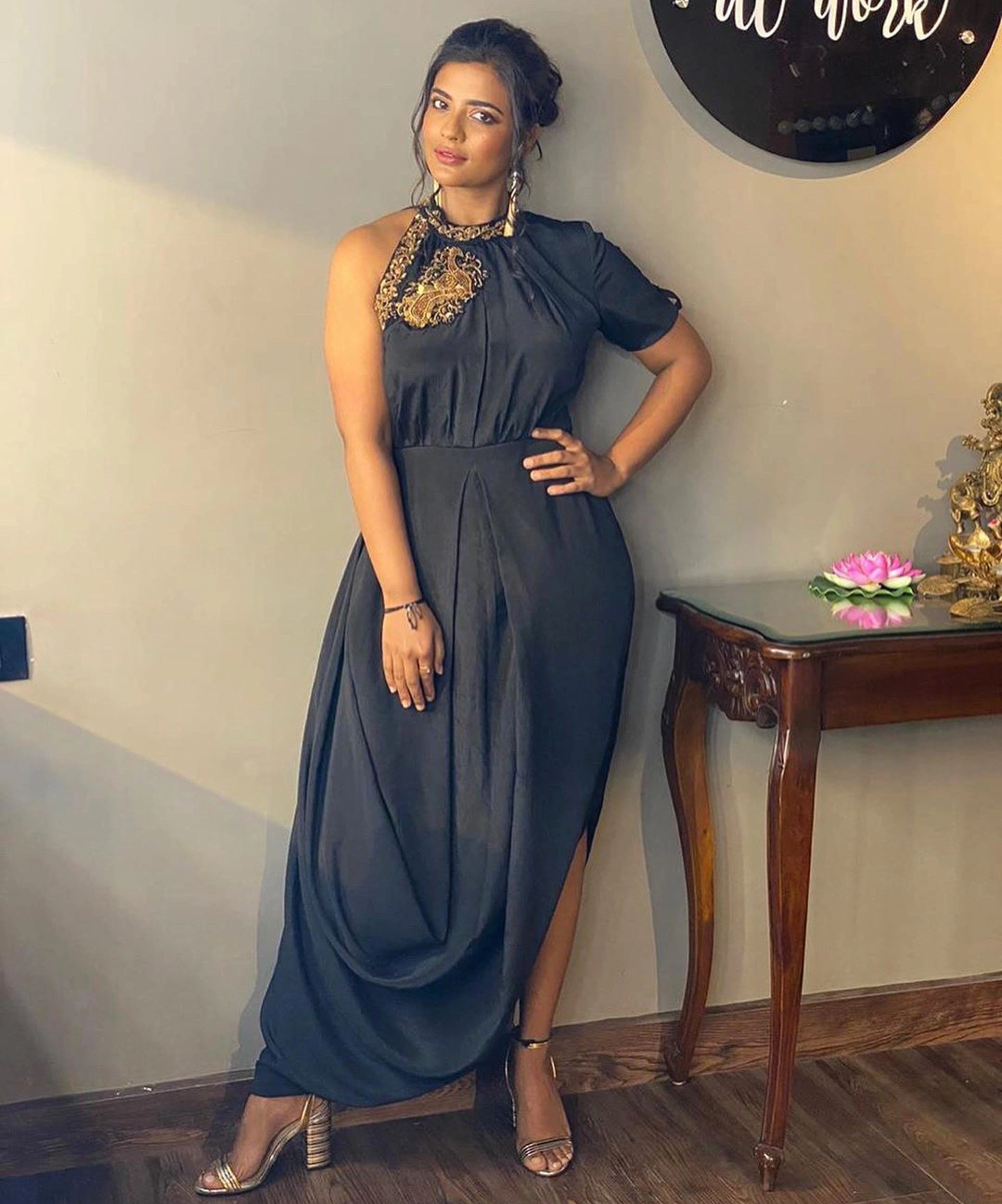 Actress Aishwarya Rajesh in a charcoal chiffon halterneck dress with a single side slit and intricate detailing.