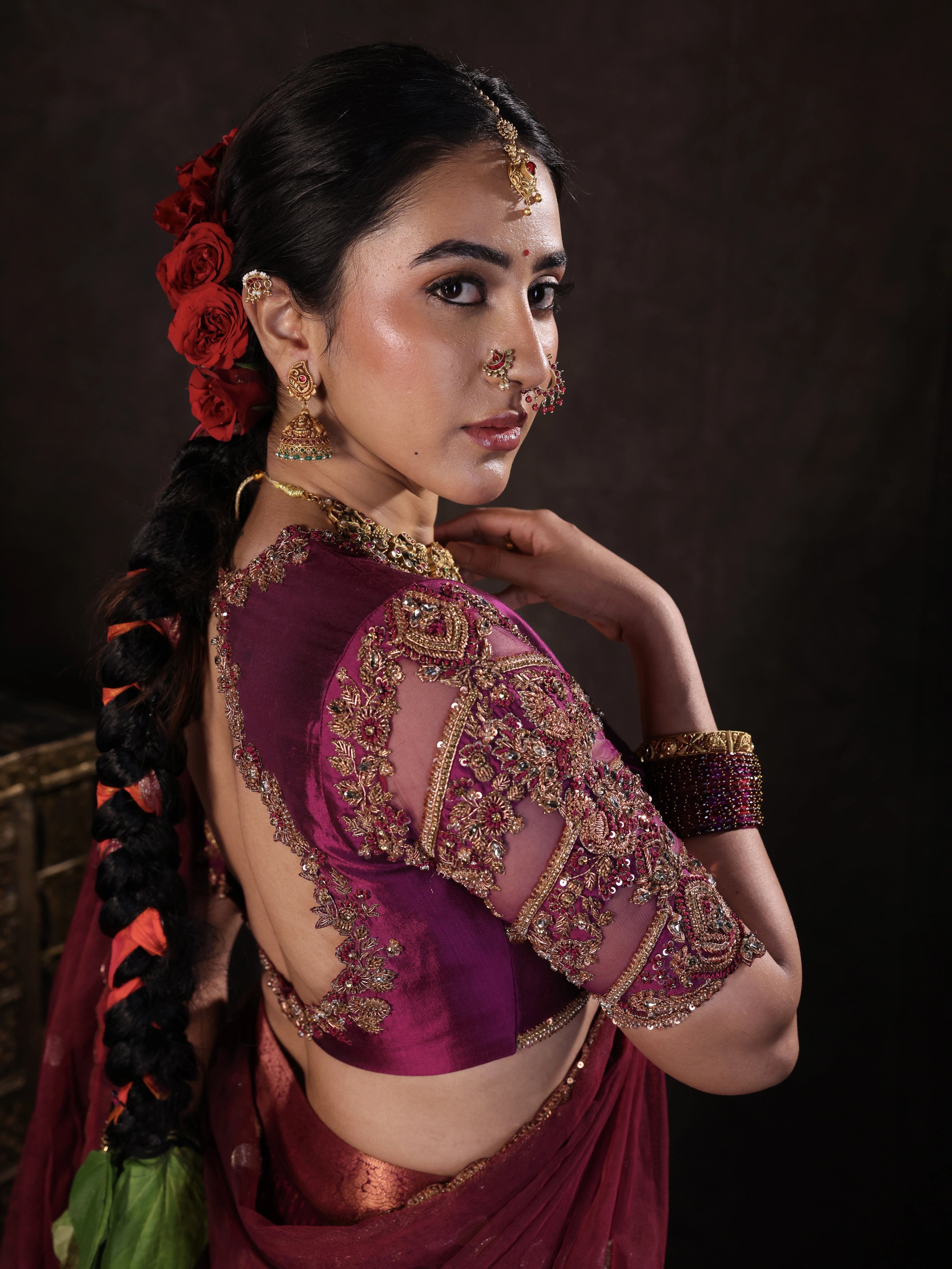 Actress Akshaya Hariharan showcasing sleeve detailing in a dark magenta silk half saree set handcrafted with zardozi, resham, cutdana, sequins & rhinestones. Team Archana Karthick completed the style with dark magenta glass bangles, a ring, jhumkas, nose ring and a maang tikka.