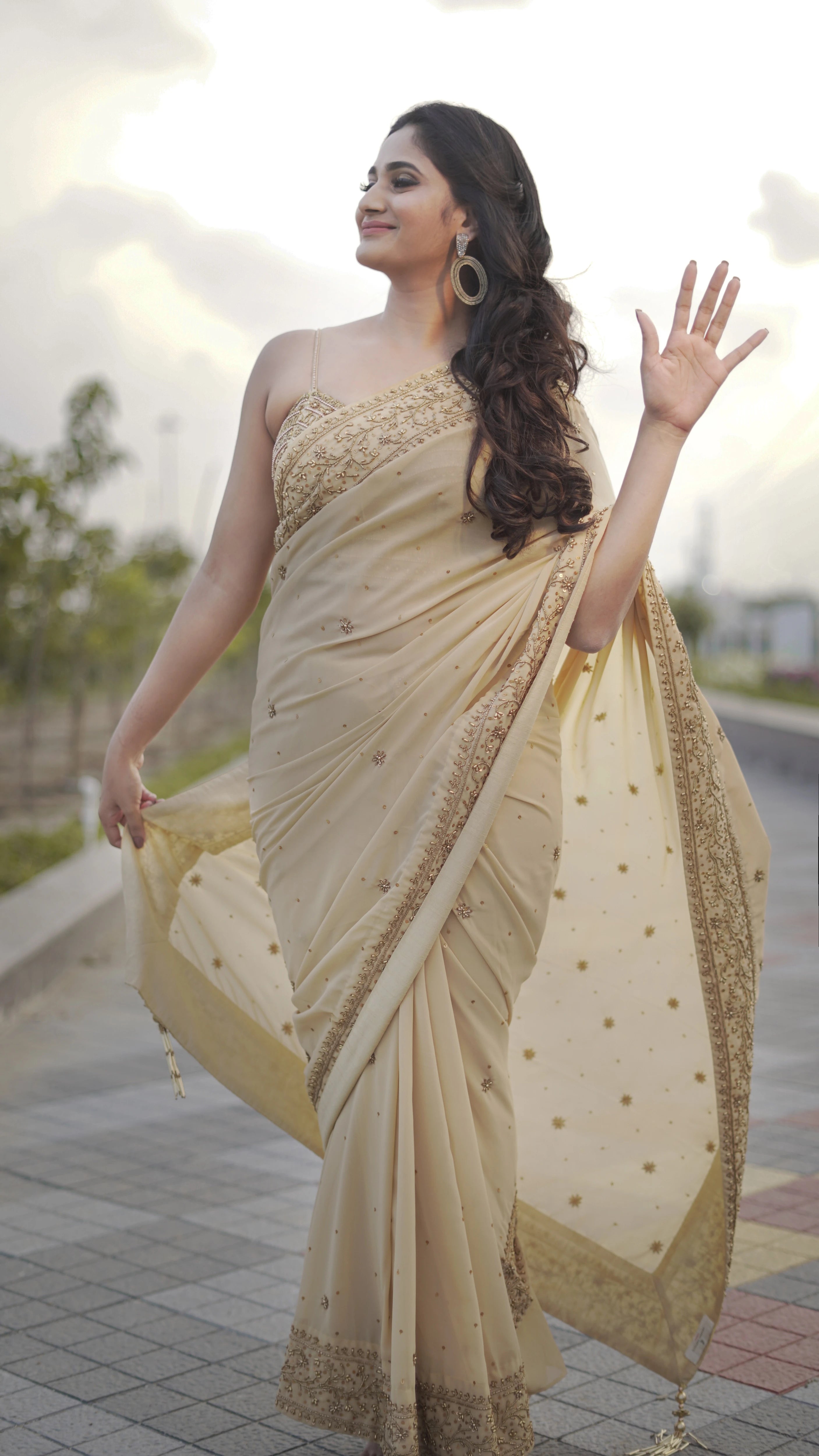 Actress & Bigg Boss fame Losliya posing during photoshoot in a beige georgette saree paired with a bralette, handcrafted with beads, sequins and pearls by team Archana Karthick.