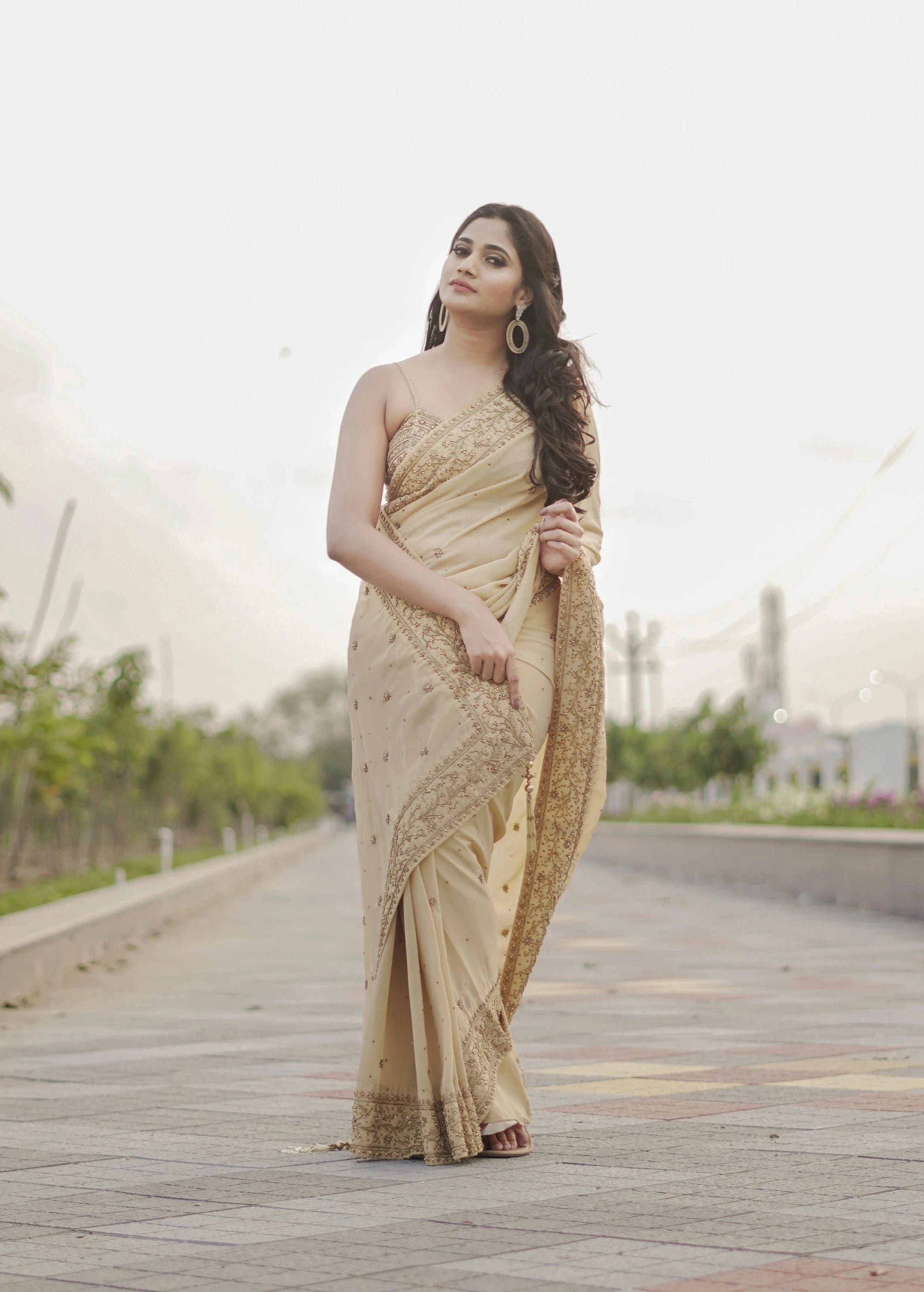 Actress & Bigg Boss fame Losliya posing for photoshoot in a beige georgette saree paired with a bralette, handcrafted with beads, sequins and pearls by team Archana Karthick.