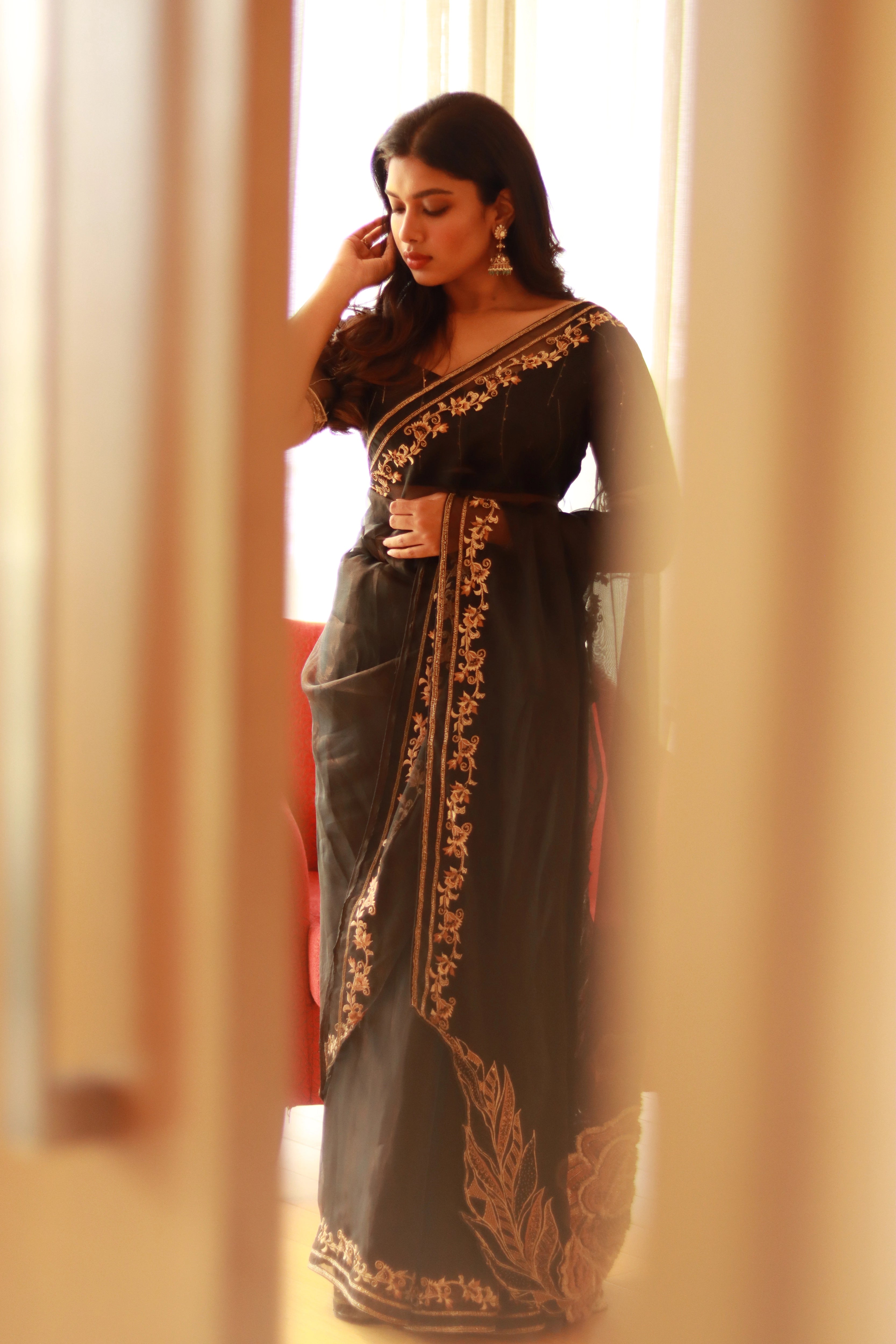 Actress Dushara Vijayan posing in a black organza saree, intricately handcrafted with cutdana, zari, beads, sequins and resham by team Archana Karthick.
