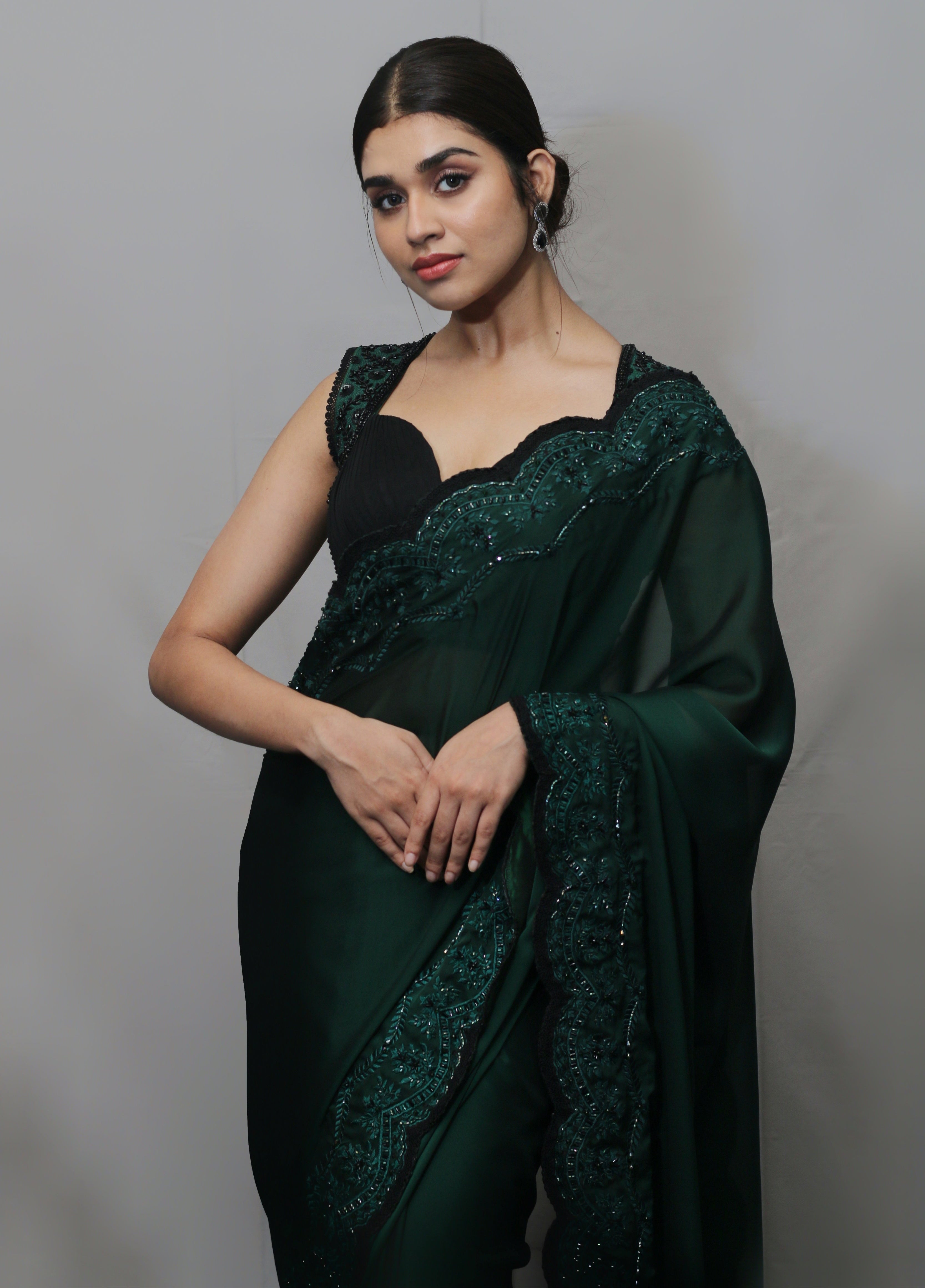 Actress Meenakshi Govindarajan in bottle green satin georgette saree set posing looking at the camera