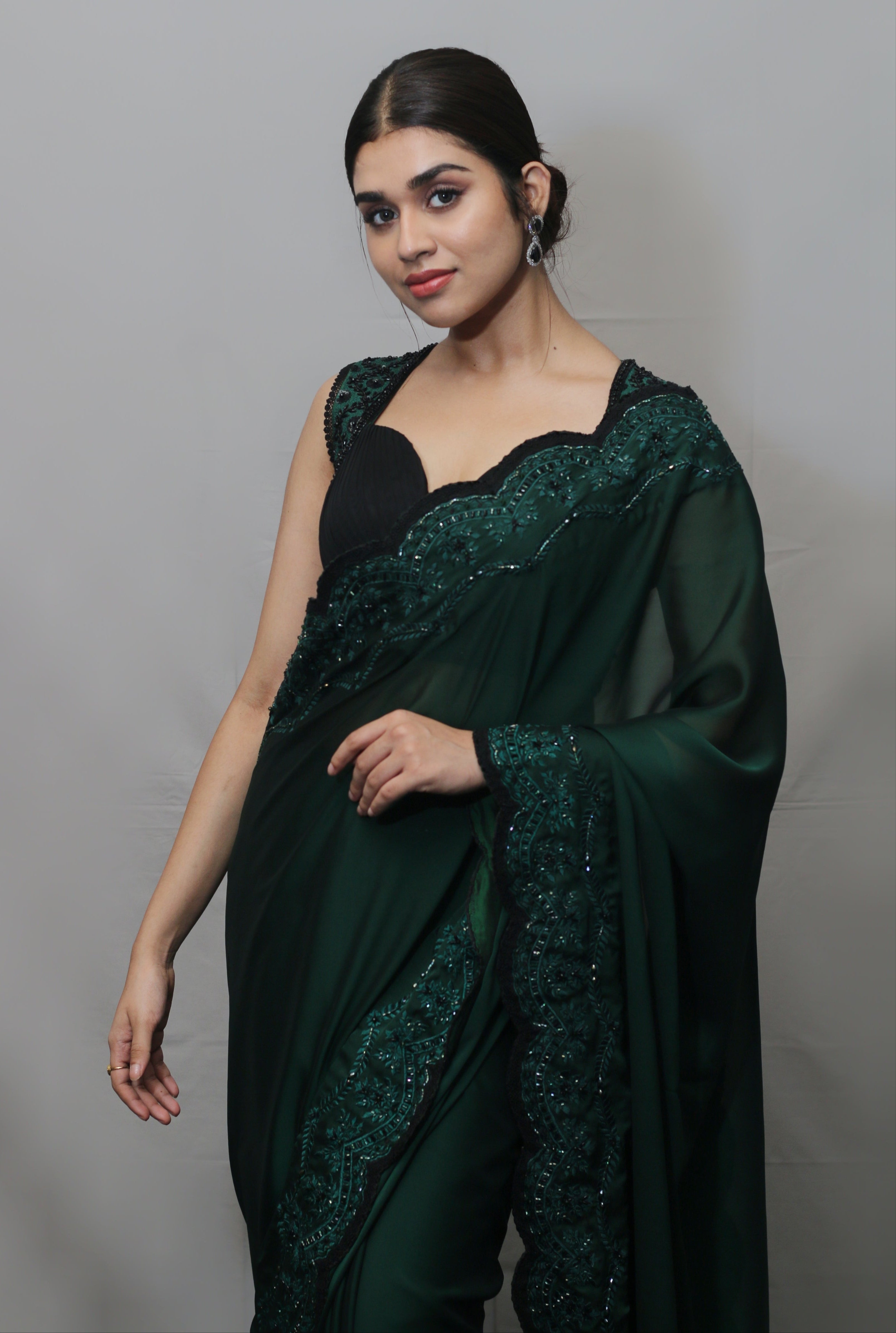 Actress Meenakshi Govindarajan in bottle green satin georgette saree set smiling at camera