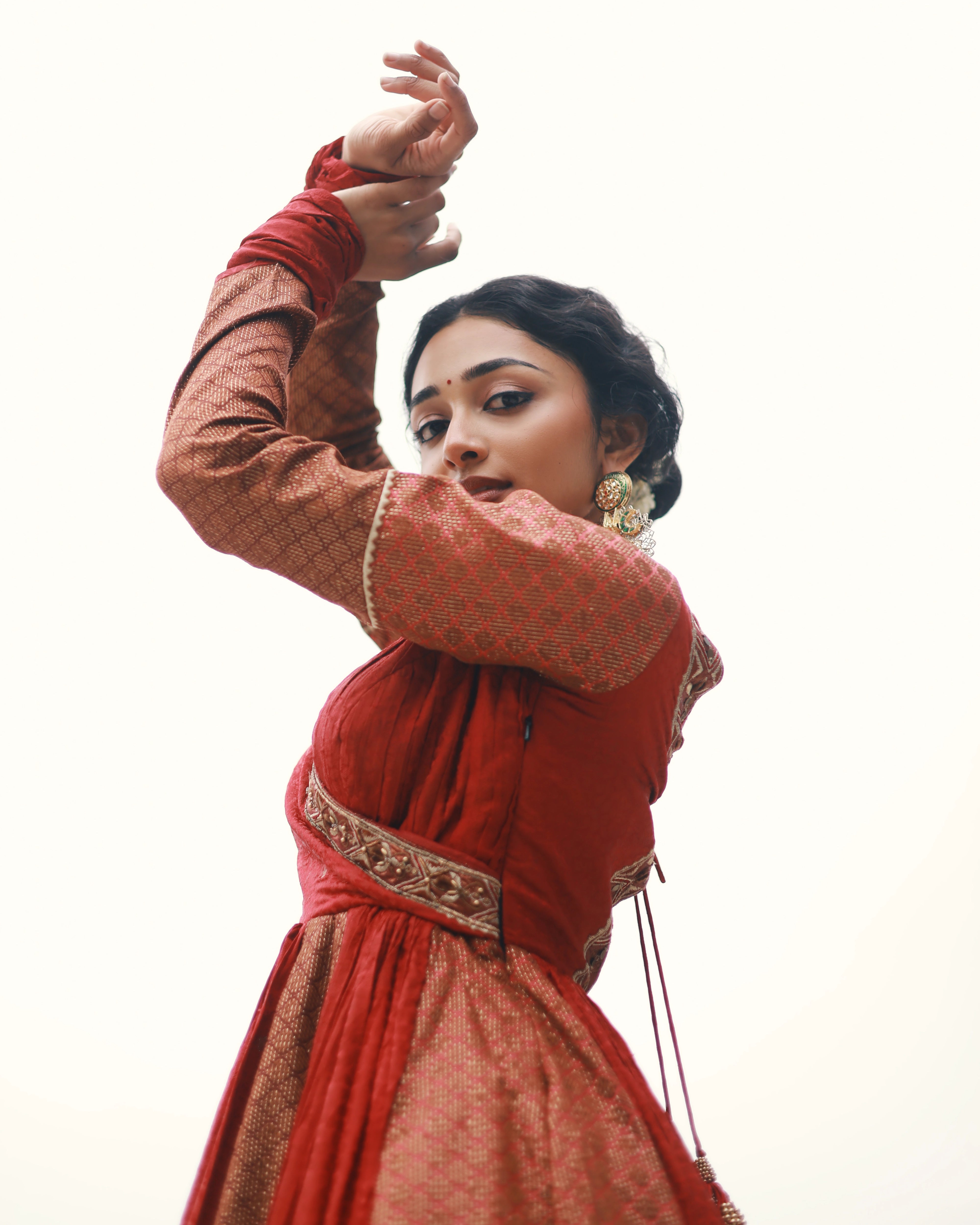 Actress Preity Mukhundhan for photoshoot in a red-orange banarasi tissue and silk angrakha anarkali with a sharara pant and tissue dupatta by team Archana Karthick.