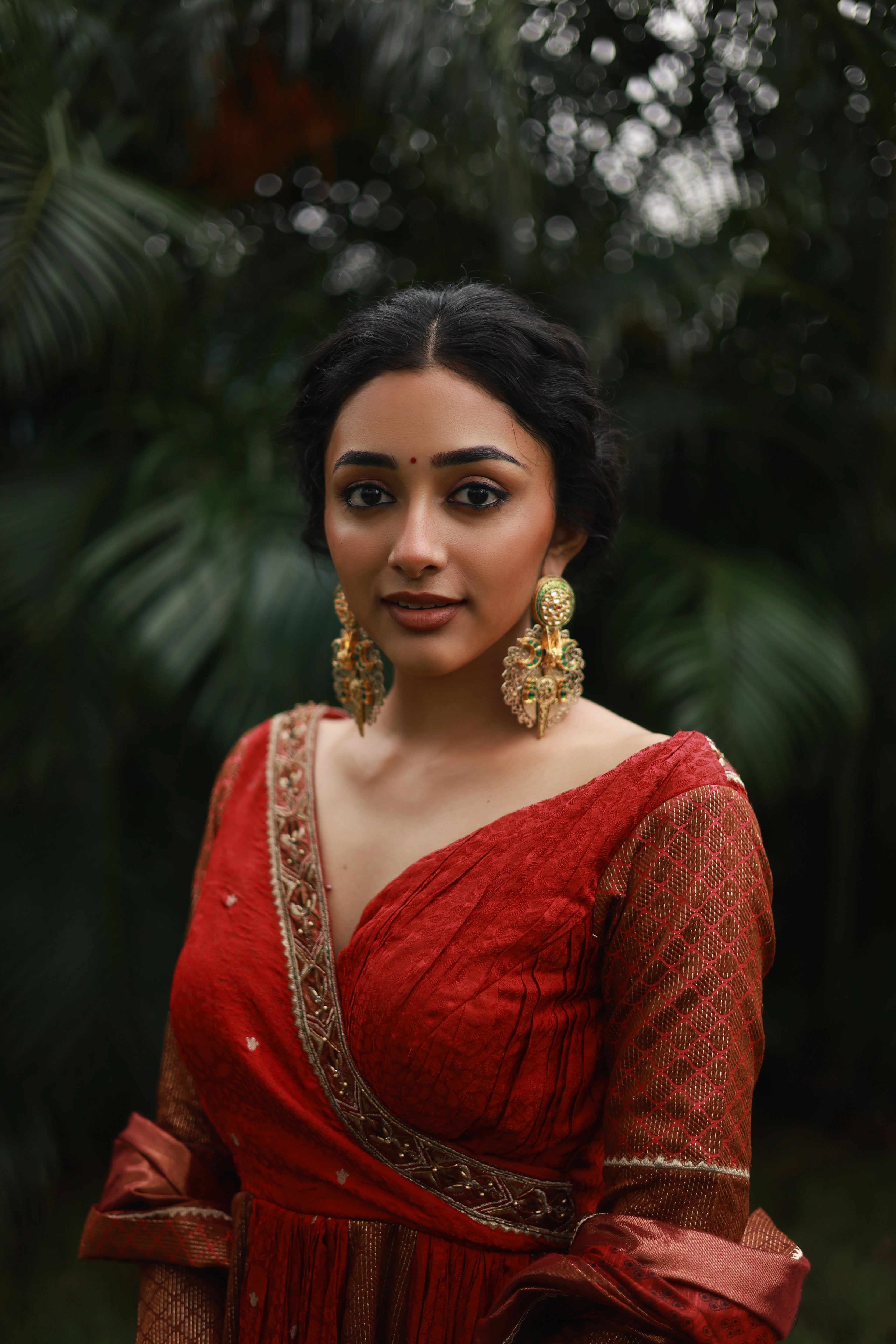 Actress Preity Mukhundhan smiling in a red-orange banarasi tissue and silk angrakha anarkali with a sharara pant and tissue dupatta by team Archana Karthick.