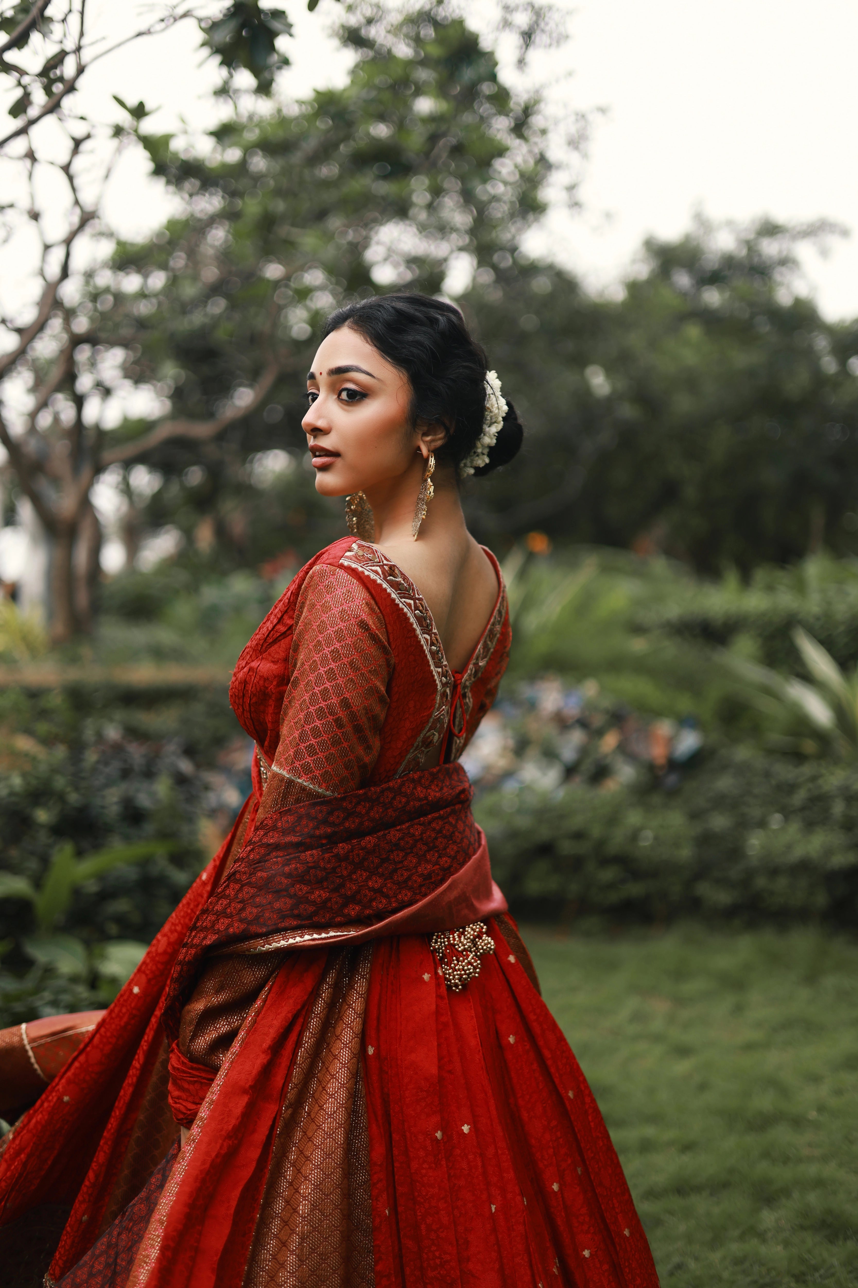 Actress Preity Mukhundhan strikes a pose in a red-orange banarasi tissue and silk angrakha anarkali with a sharara pant and tissue dupatta by team Archana Karthick.