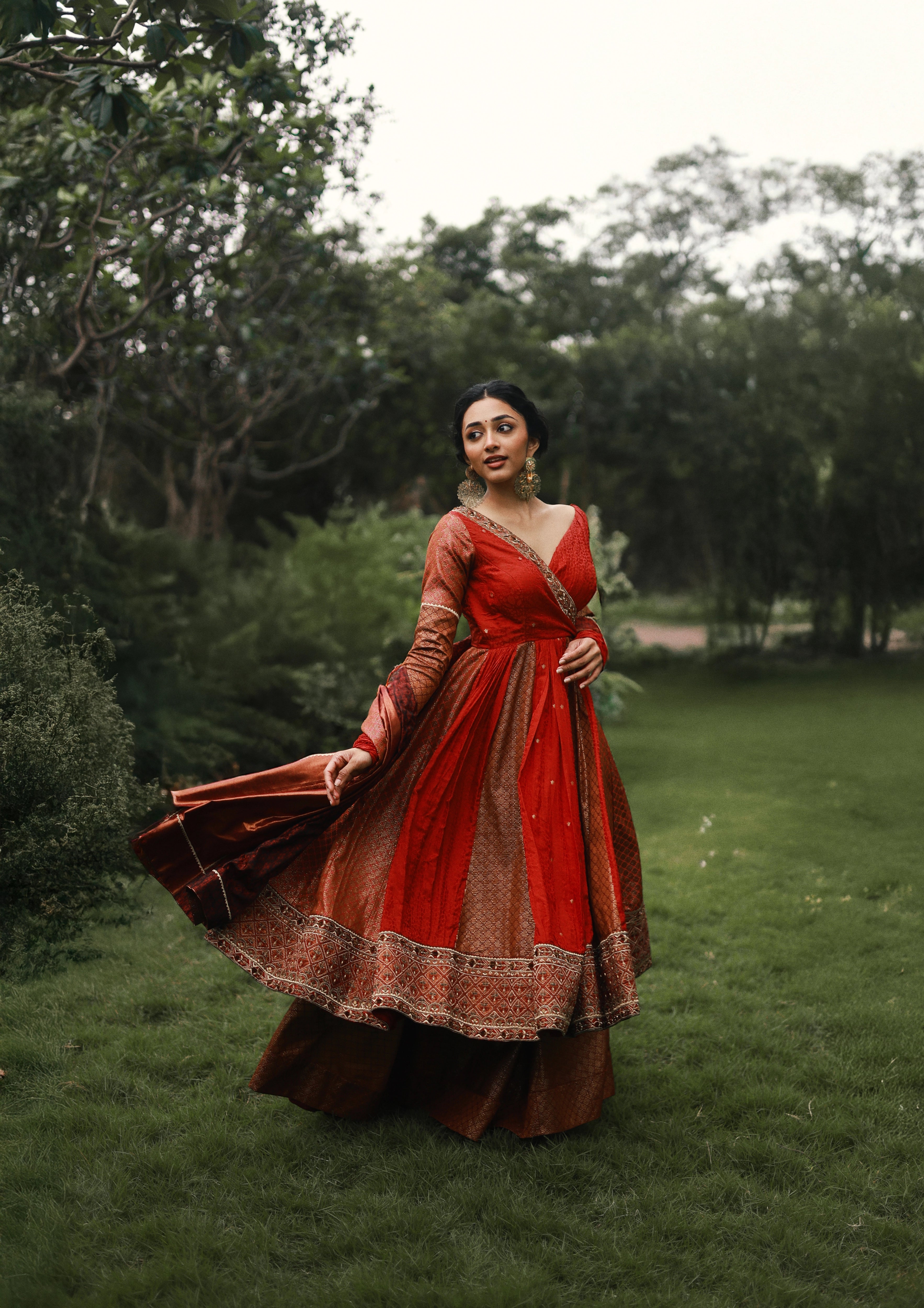 Actress Preity Mukhundhan twirls in a red-orange banarasi tissue and silk angrakha anarkali with a sharara pant and tissue dupatta by team Archana Karthick.