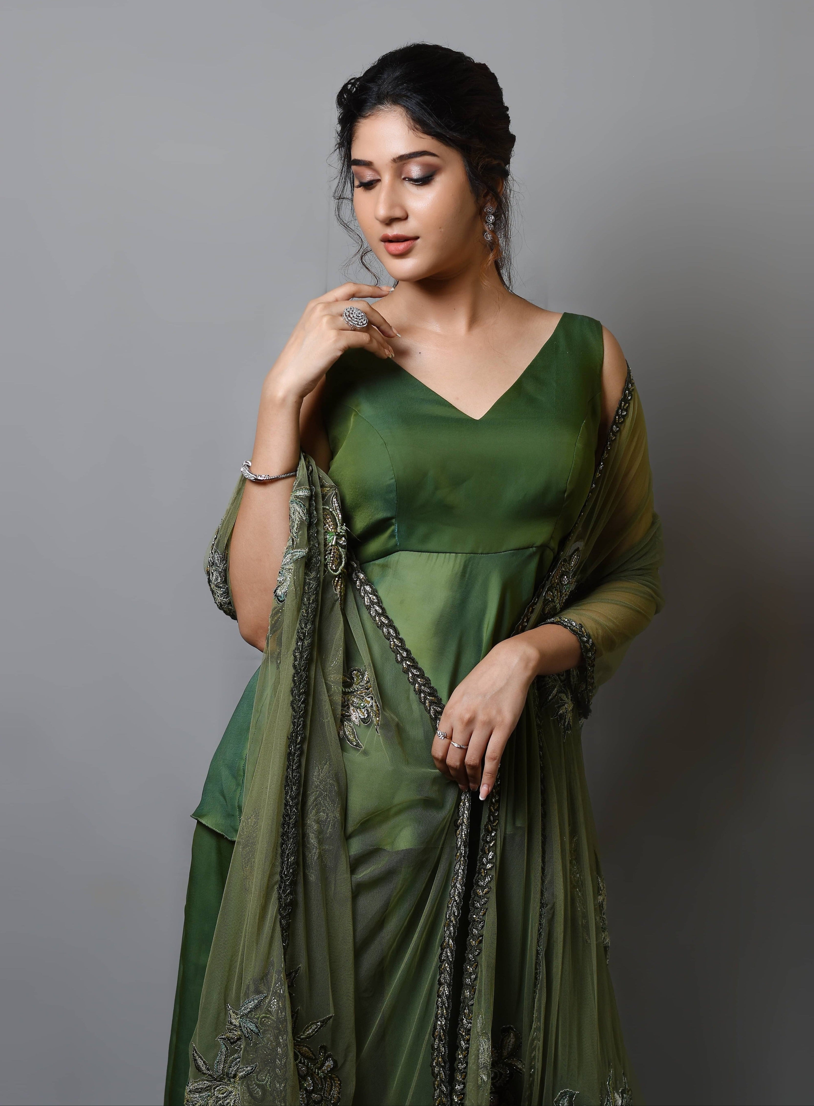 Actress Rabiya Khatoon in a green satin georgette peplum sharara palazzo set with embellished dupatta. hand on her chin