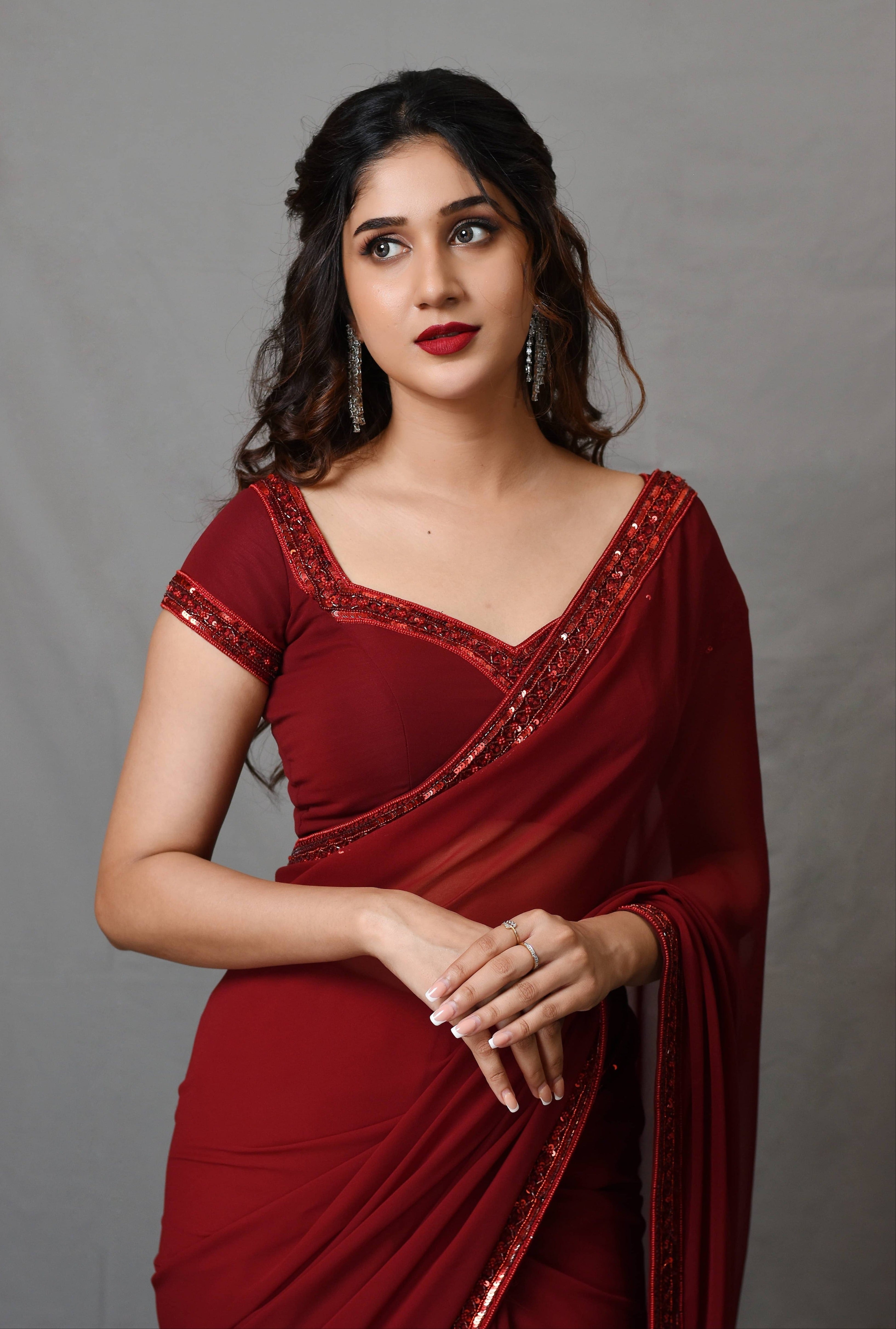 Actress Rabiya Khatoon in a ruby red georgette saree set designed by Archana Karthick. front profile.