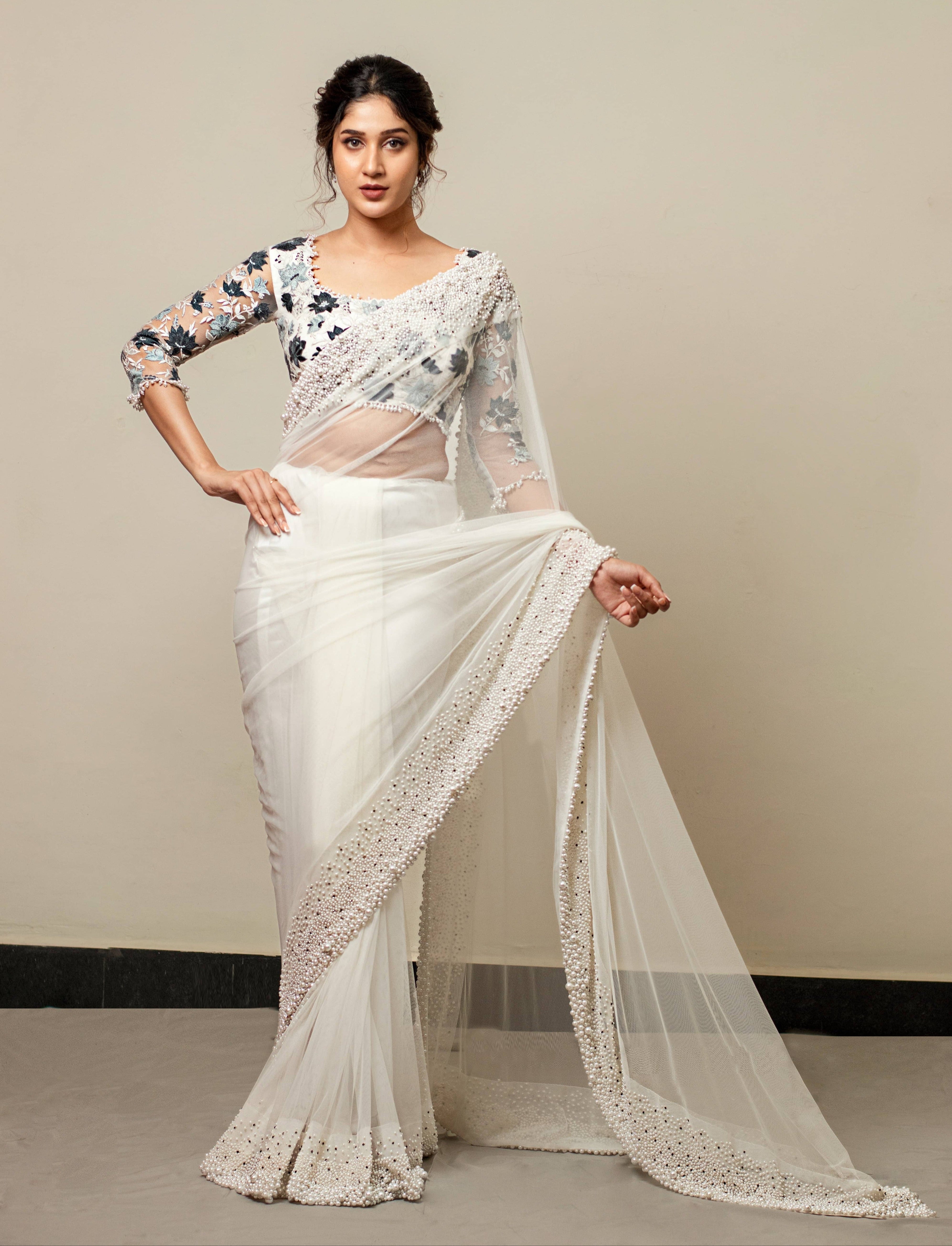 Actress Rabiya Khatoon in white net saree with pearl embellished border and blue florals in resham full sleeved blouse. Full front profile saree pallu flare.
