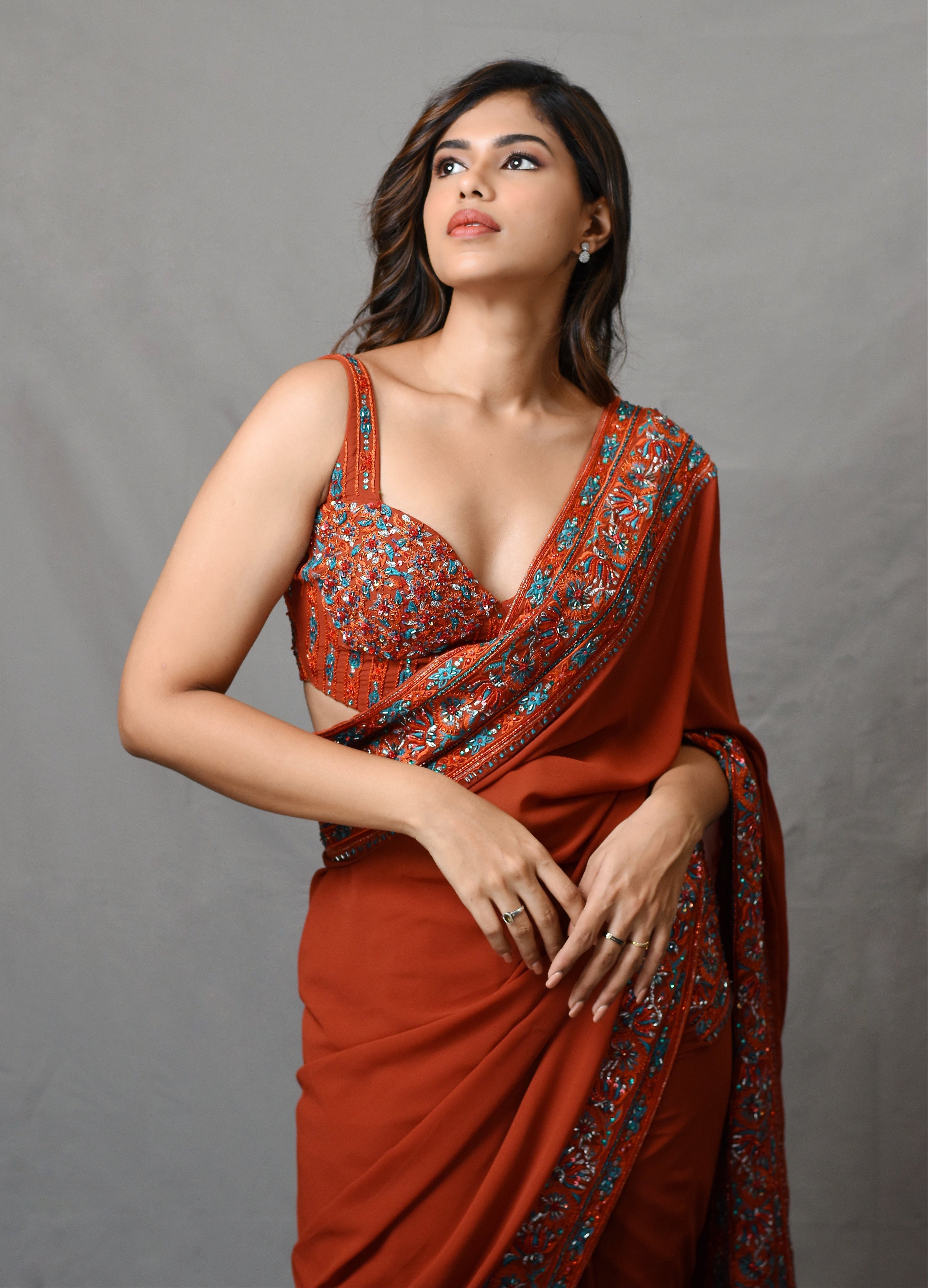 Actress Shrisha posing in a burnt orange crepe silk saree with an intricately handcrafted border and corset blouse from the Lo-Mance collection by Archana Karthick.