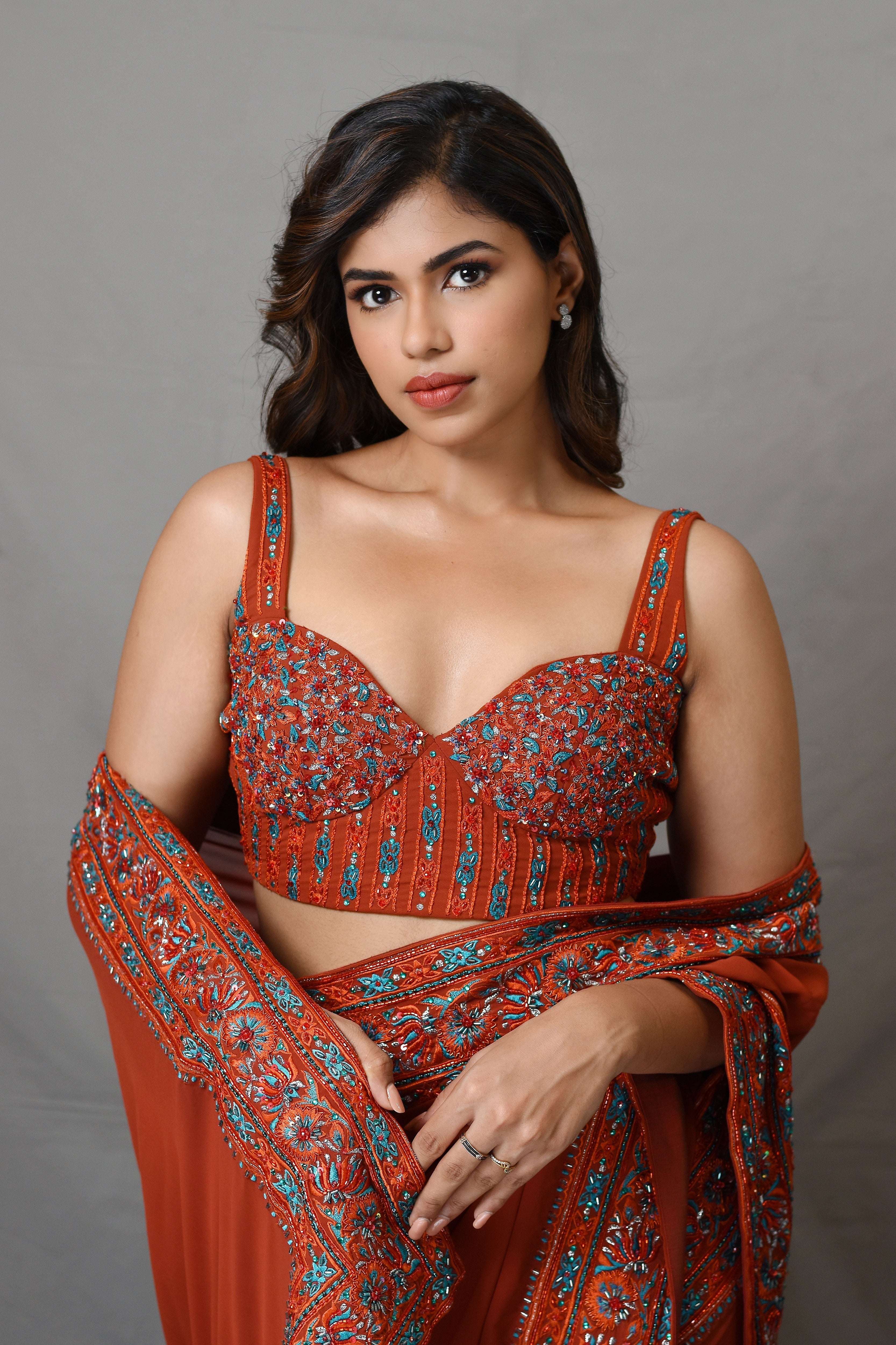 Actress Shrisha smilng for corset detailings in a burnt orange crepe silk saree with an intricately handcrafted border and corset blouse from the Lo-Mance collection by Archana Karthick.
