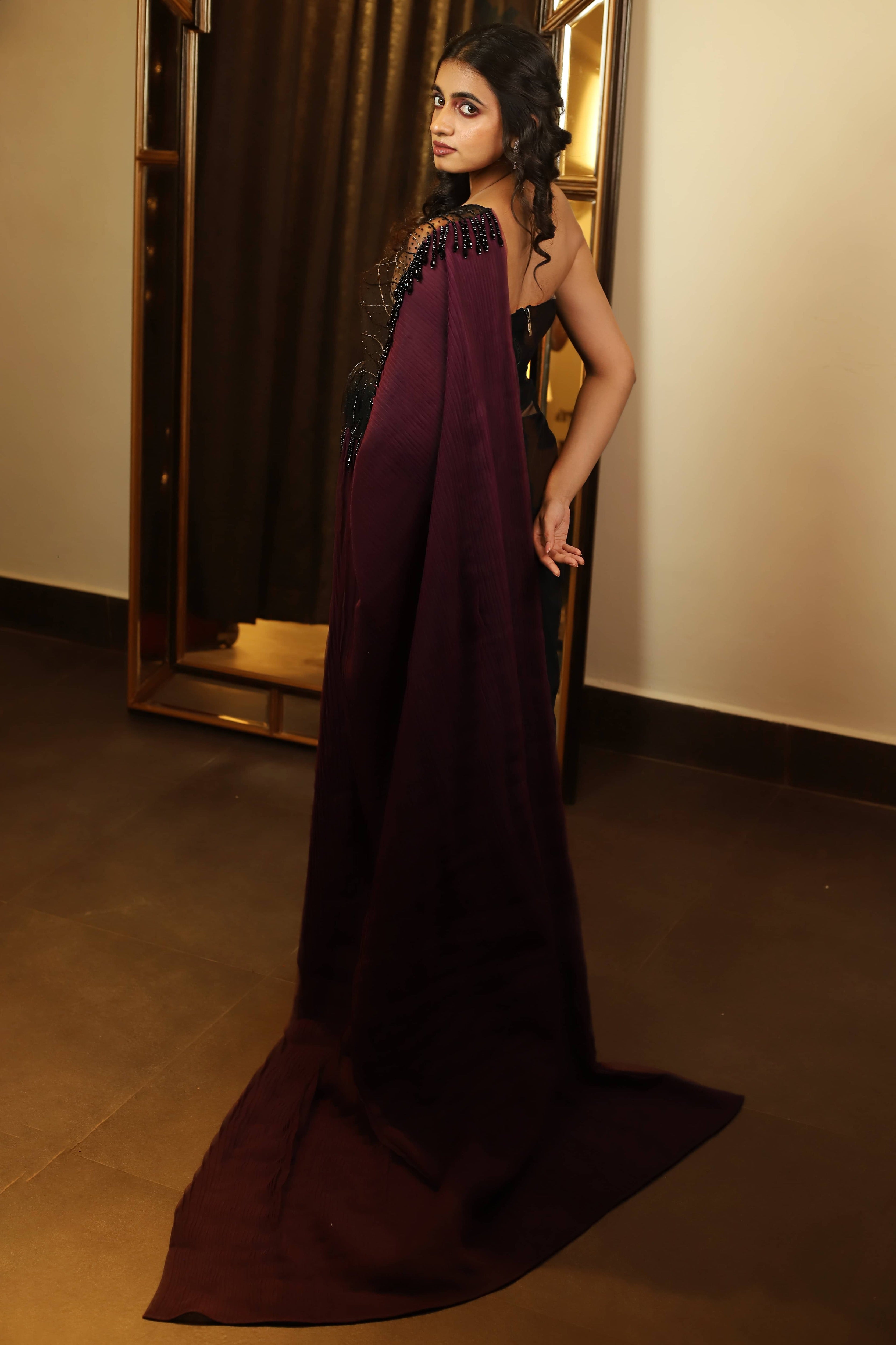 Actress and Model Cherukuri Maanasa Choudhary who acted in Lucky Baskhar in a black aubergine saree and bralette set with cut dana detailings. back detailing of saree and hangings on pallu.