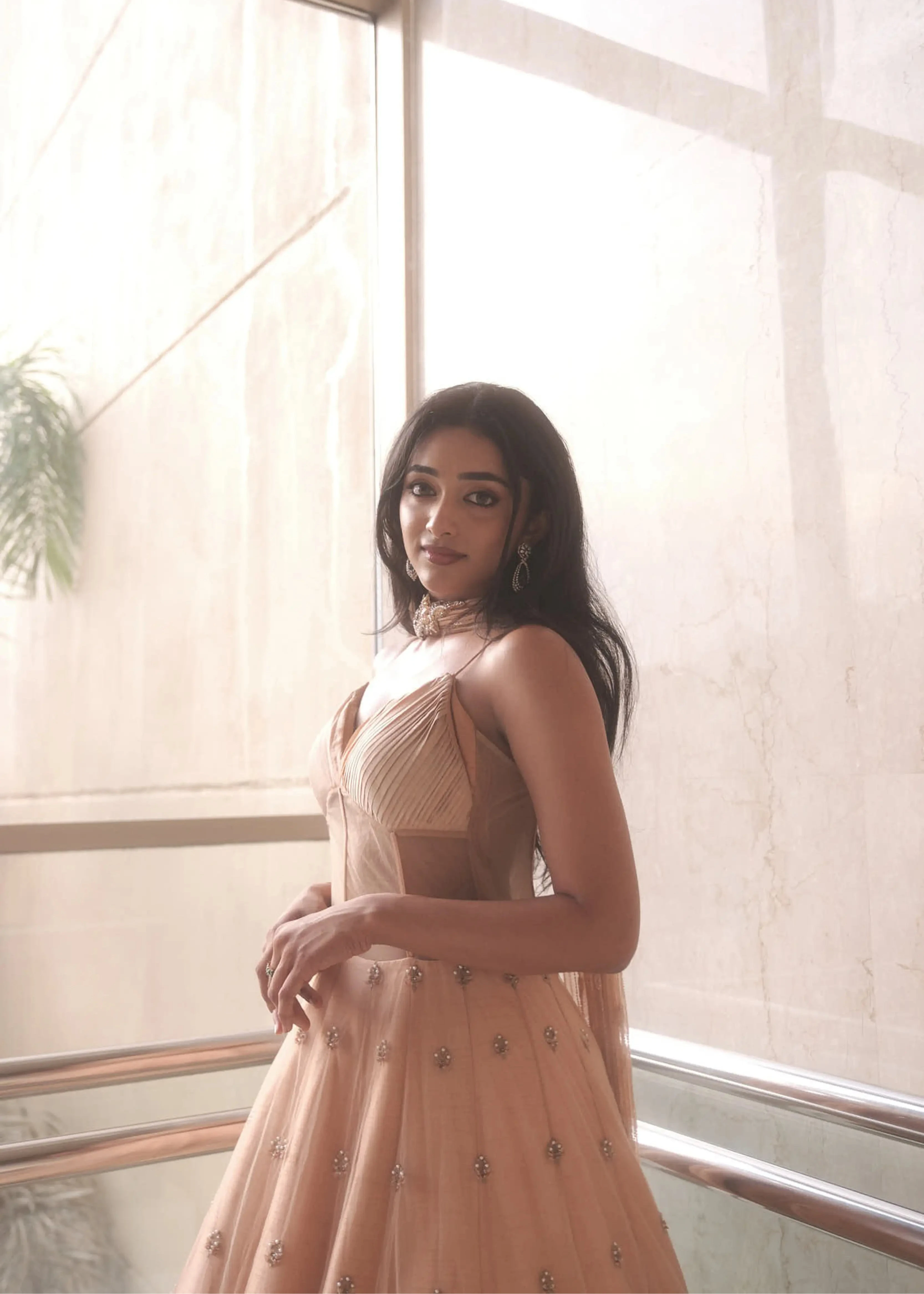 Actress & dancer Preity Mukhundhan looking at the lens in a peach corset gown with draped dupatta attached at the neck, intricately handcrafted by team Archana Karthick.