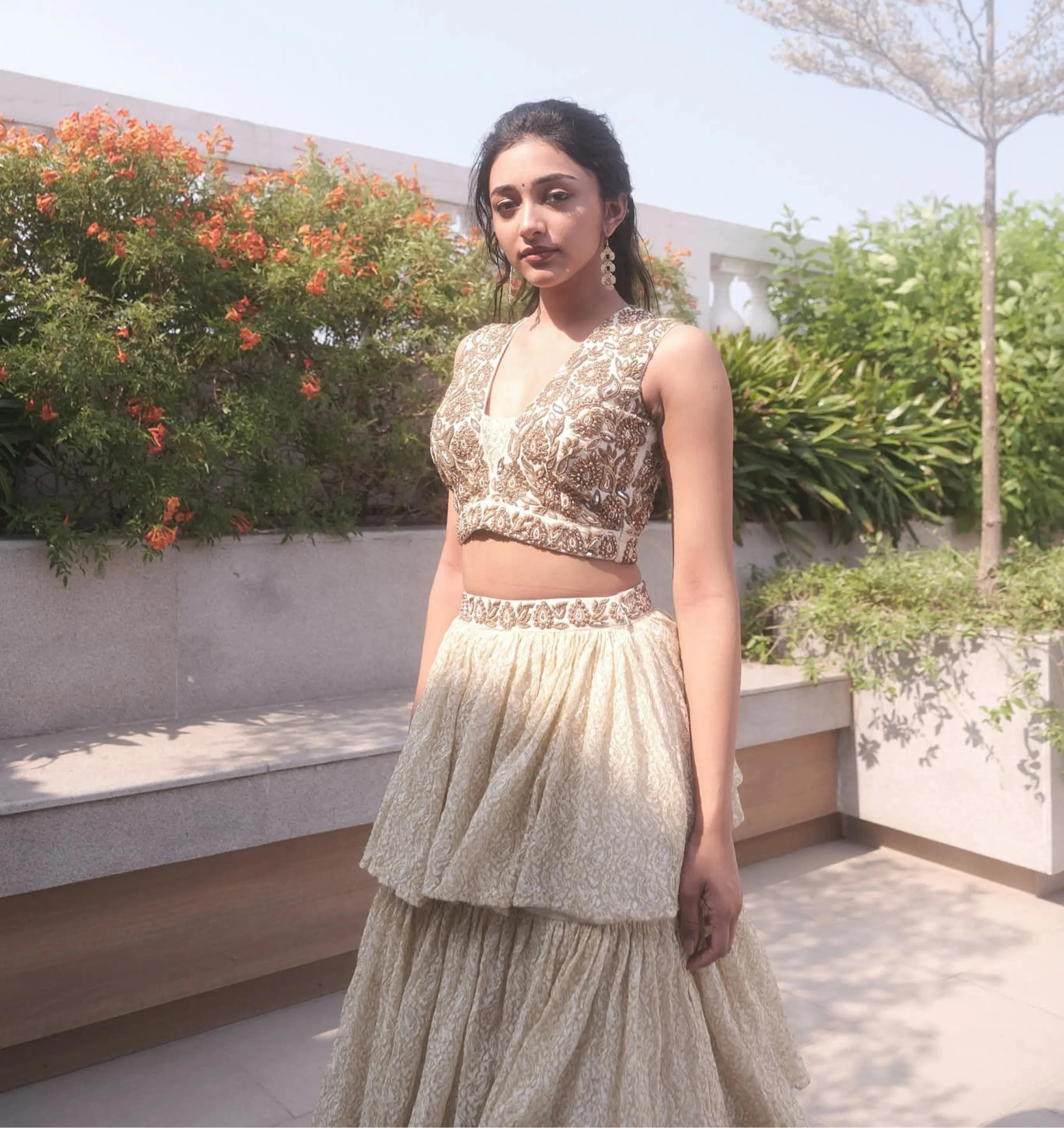 Actress & dancer Preity Mukhundhan posing during photoshoot in a plunge neck raw silk ivory crop-top bralette and layered skirt in brasso fabric with self work by team Archana Karthick.