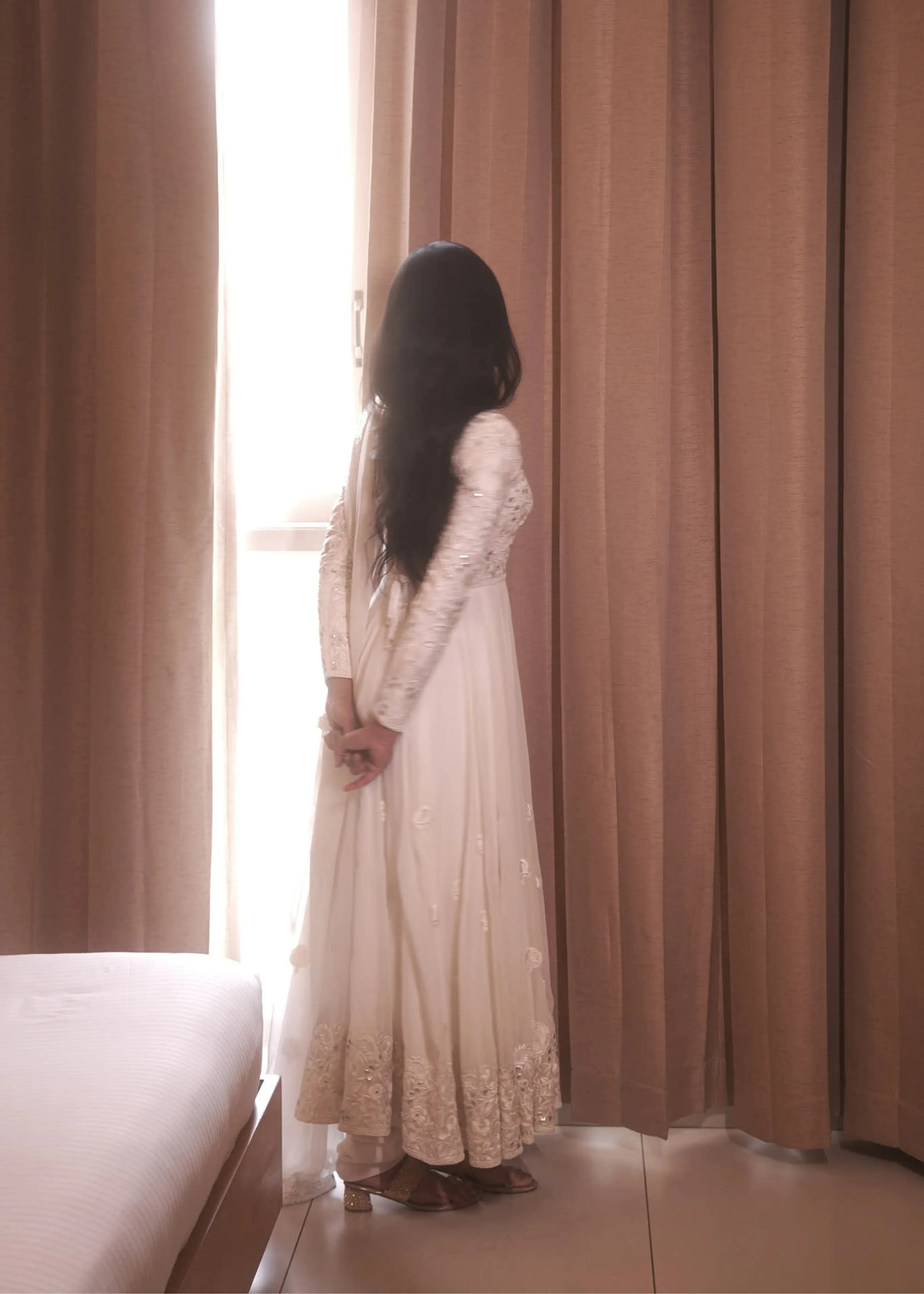 Actress & dancer Preity Mukhundhan posing for back profile in a white georgette anarkali intricately handcrafted with gotapati, resham (chikanakri work) by team Archana Karthick.