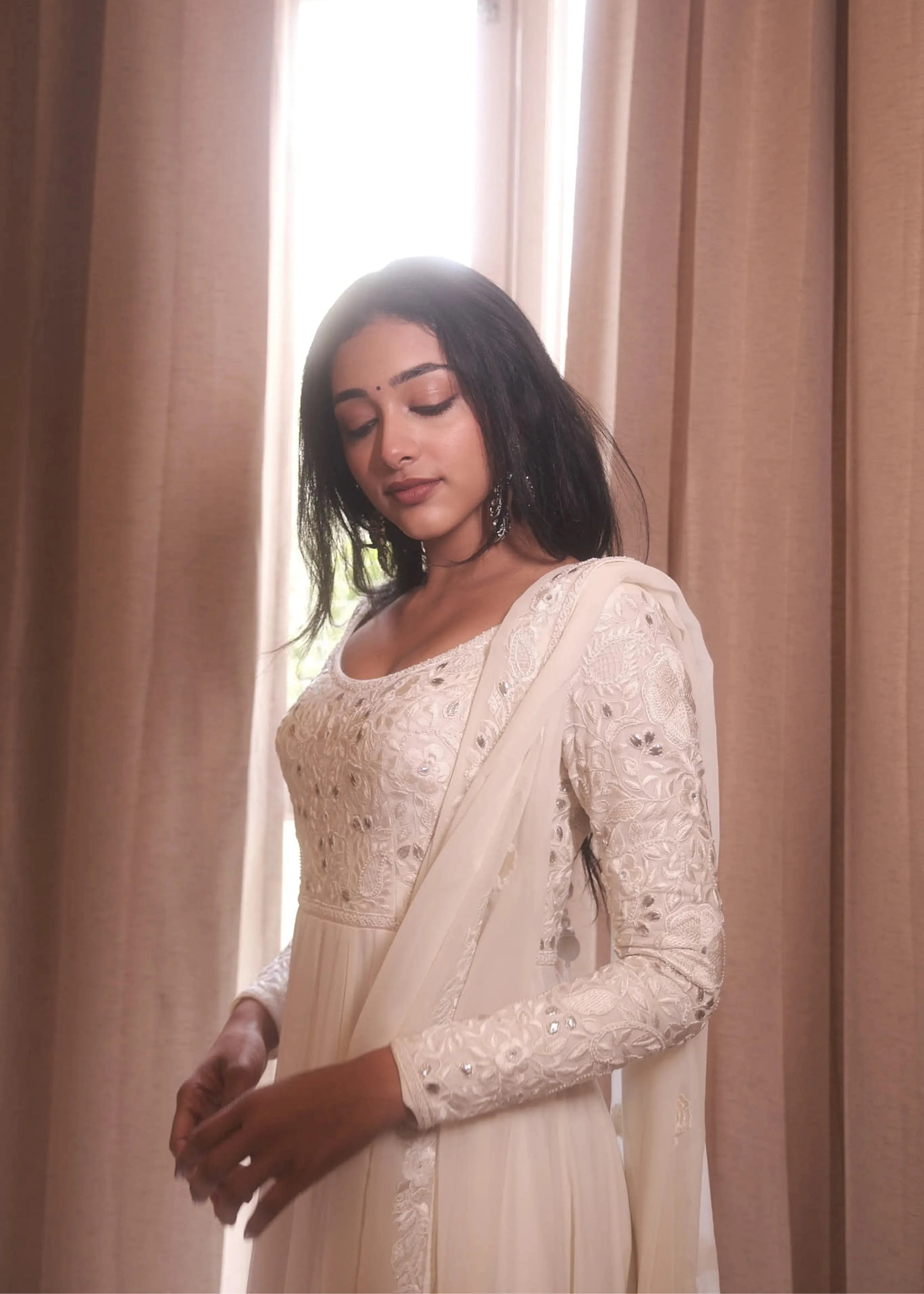 Actress & dancer Preity Mukhundhan posing for front and sleeve in a white georgette anarkali intricately handcrafted with gotapati, resham (chikanakri work) by team Archana Karthick.