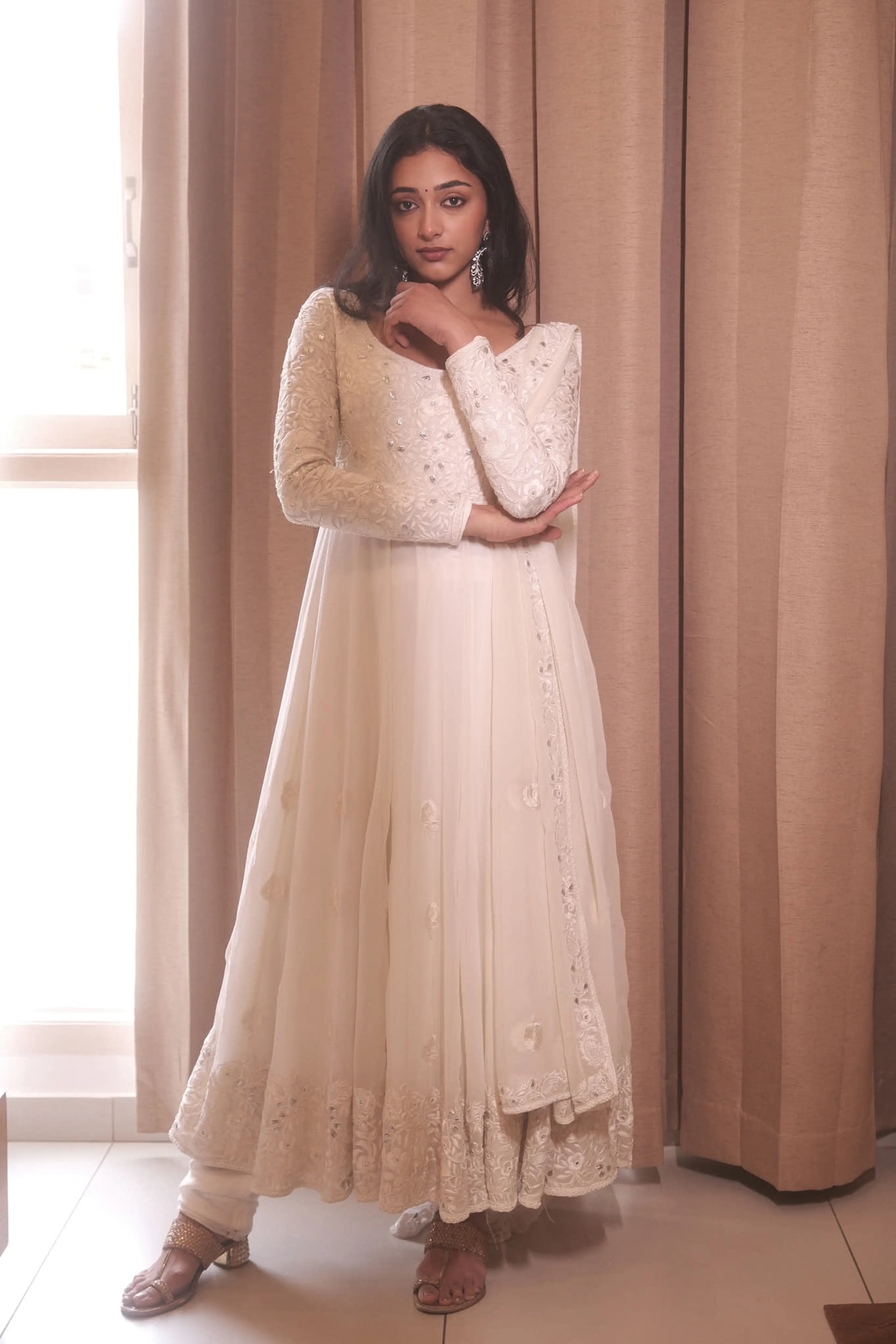Actress & dancer Preity Mukhundhan posing for front profile in a white georgette anarkali intricately handcrafted with gotapati, resham (chikanakri work) by team Archana Karthick.