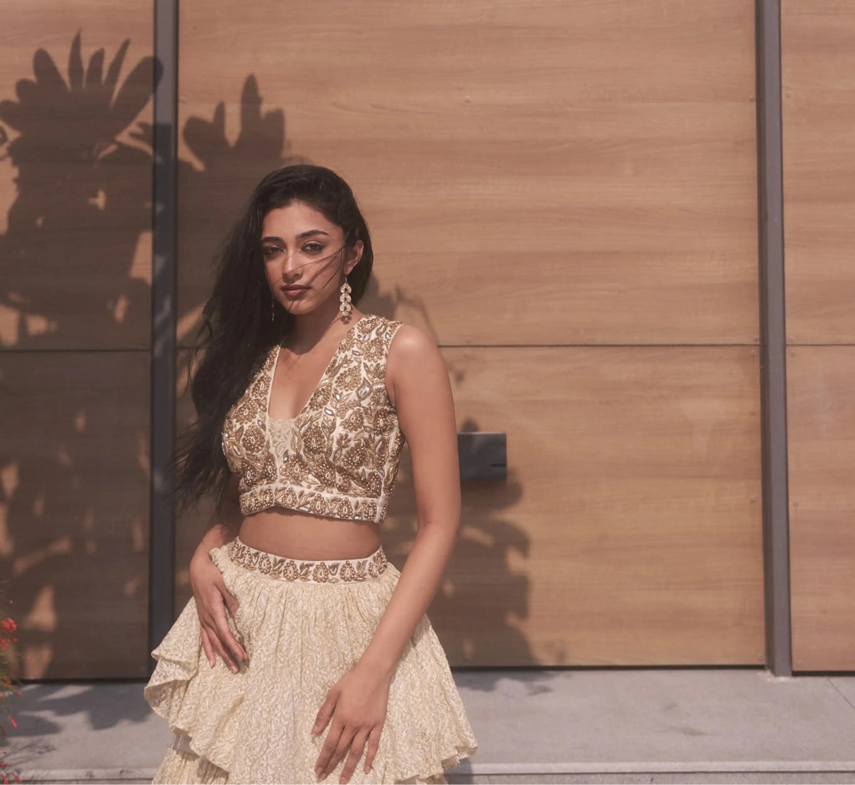 Actress & dancer Preity Mukhundhan posing for photoshoot in a plunge neck raw silk ivory crop-top bralette and layered skirt in brasso fabric with self work by team Archana Karthick.