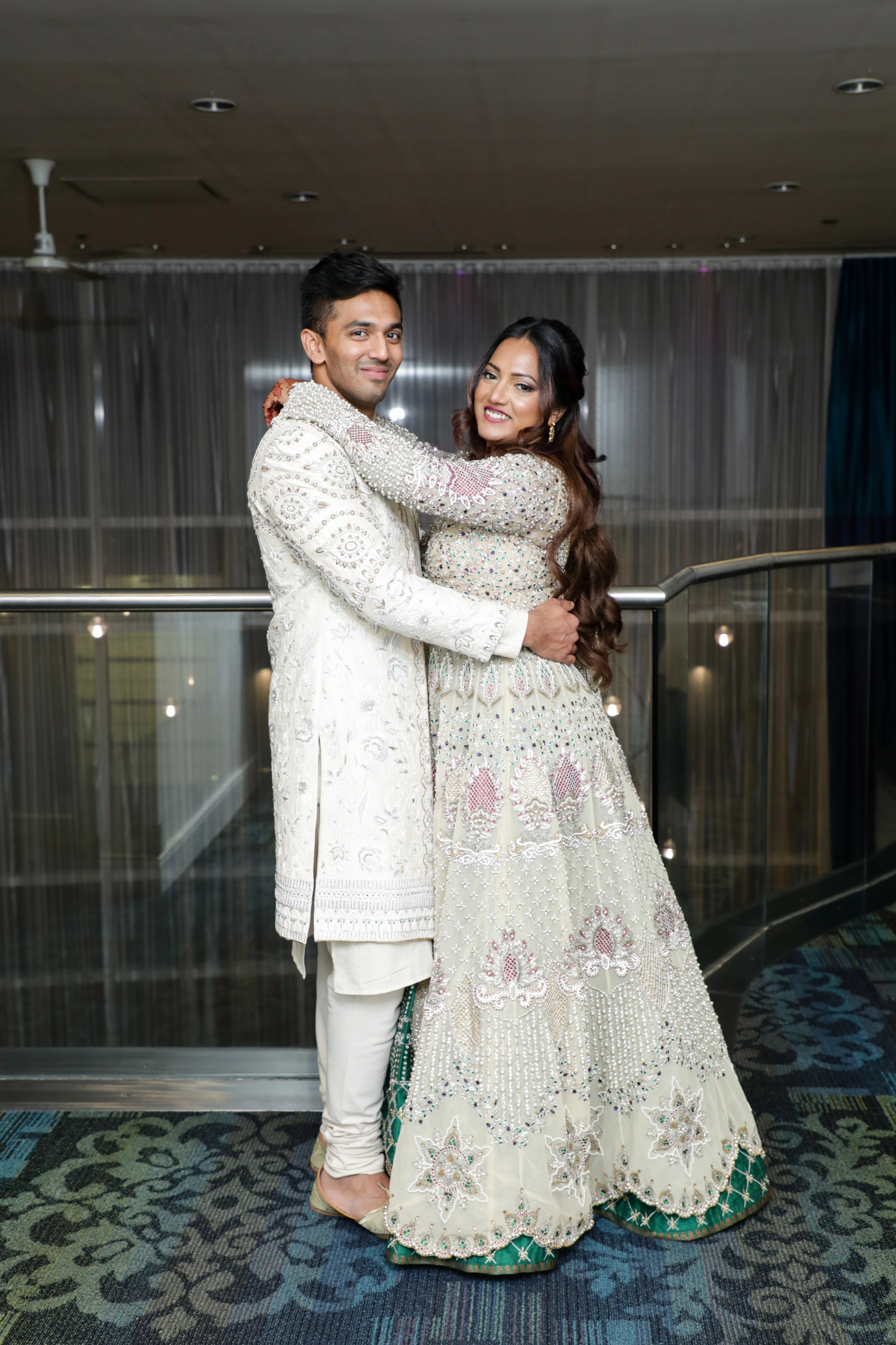 Angeline & Groom from Canada posing in an ivory masakali lehenga and sherwani handcrafted by team Archana Karthick