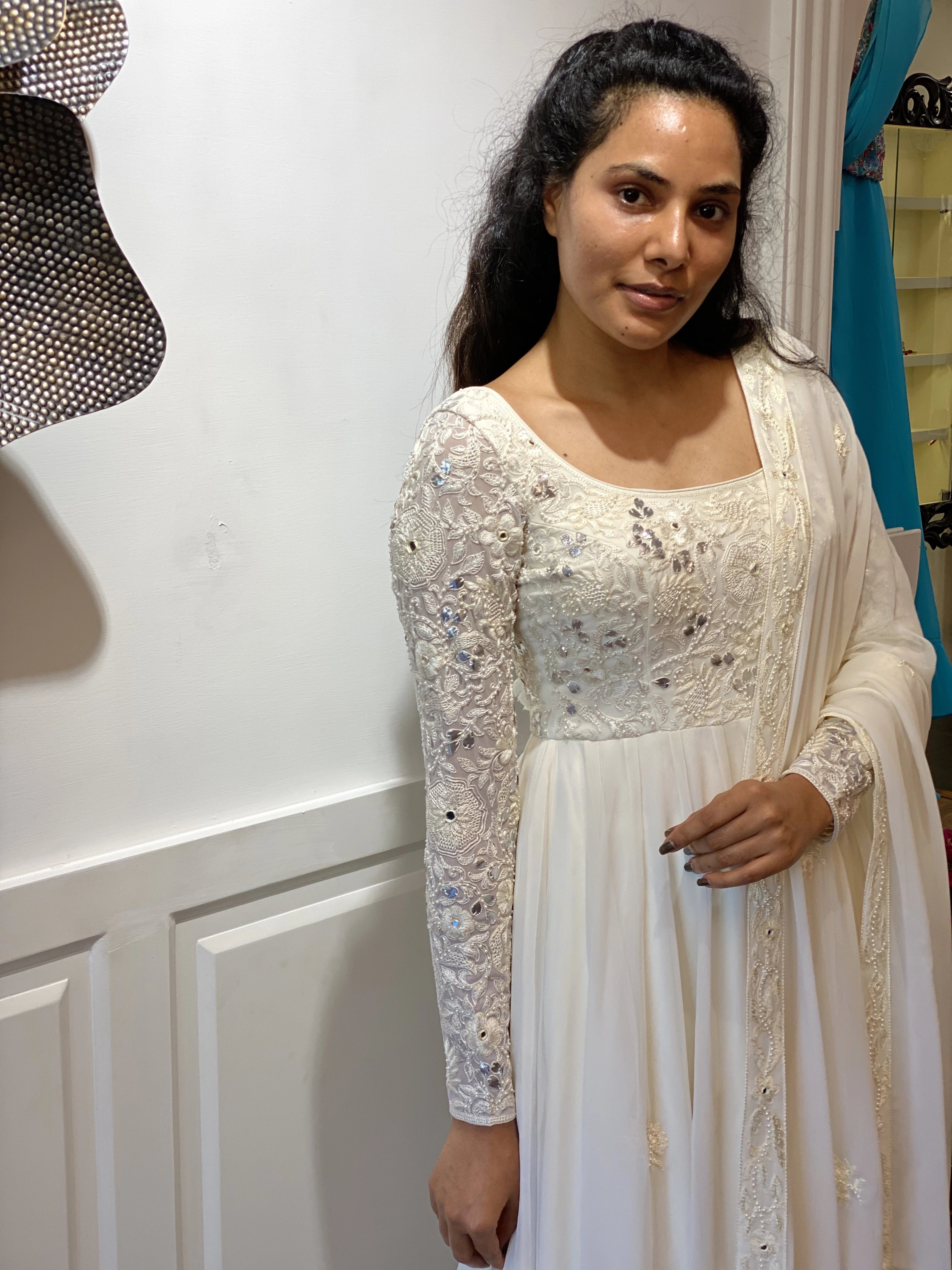 Arshitha from Bangalore looking at the lens in a white georgette anarkali, intricately handcrafted with gotapati, resham (chikanakri work) by team Archana Karthick.