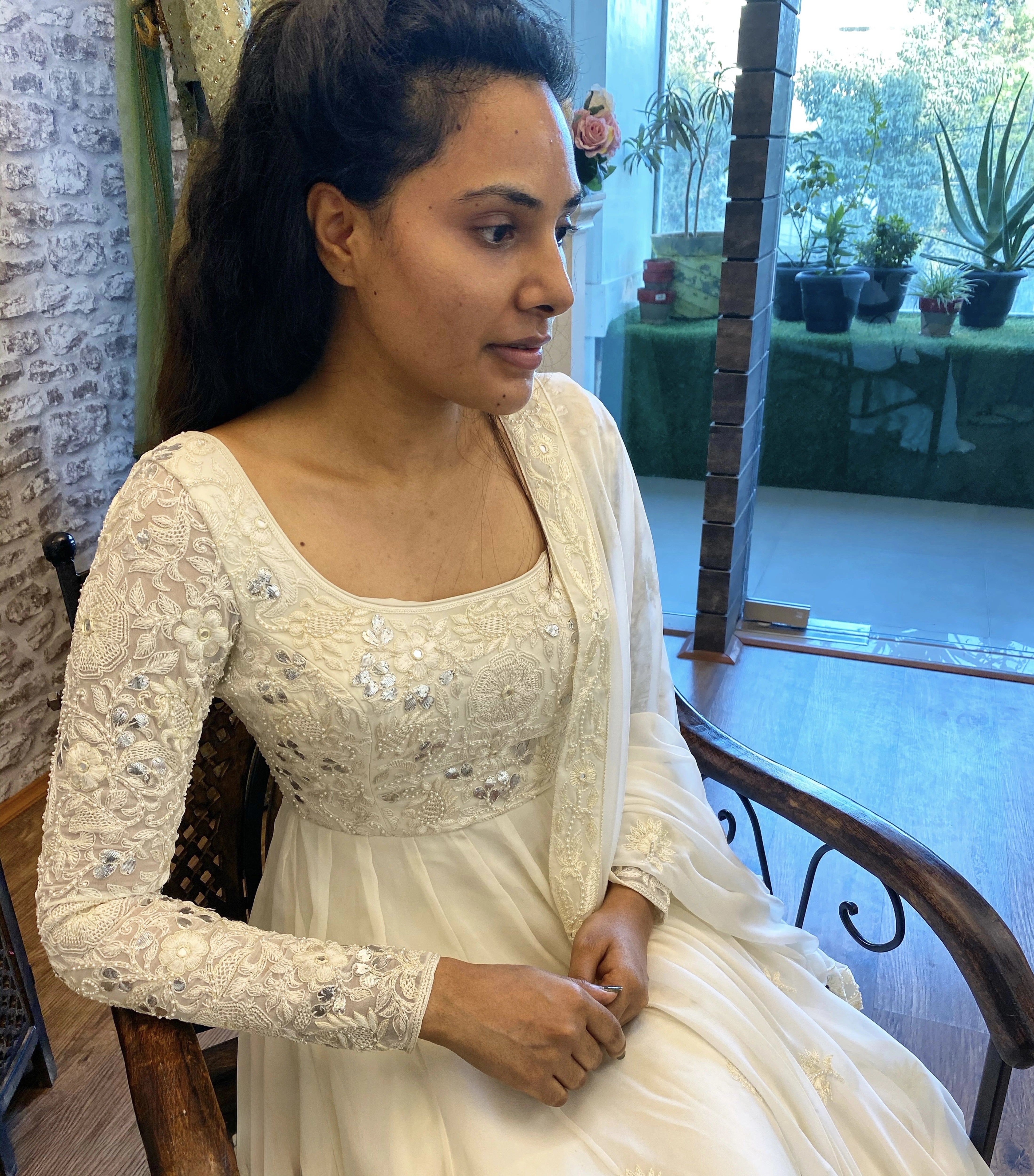 Arshitha from Bangalore looking away in a white georgette anarkali, intricately handcrafted with gotapati, resham (chikanakri work) by team Archana Karthick.