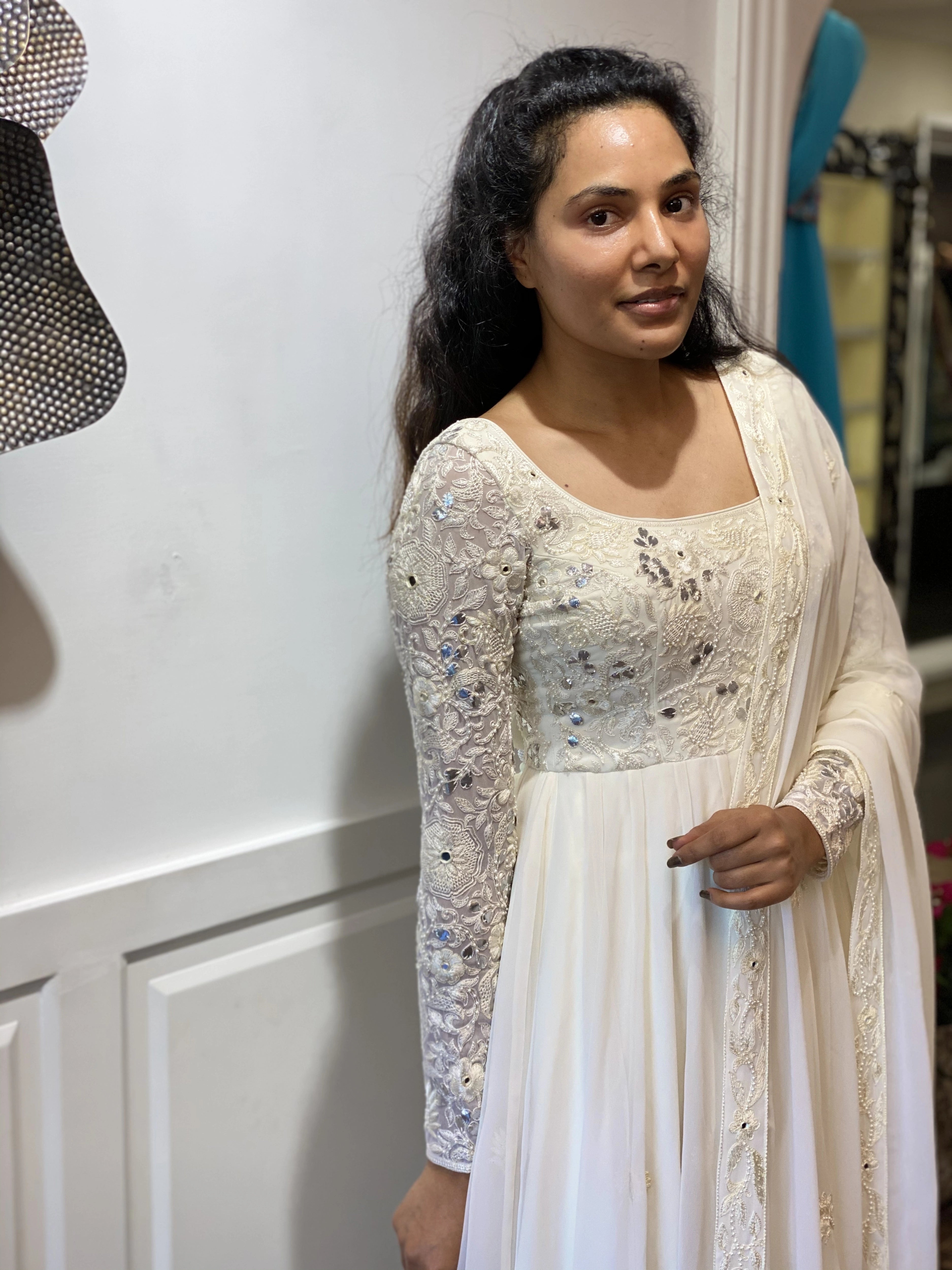 Arshitha from Bangalore smiling in a white georgette anarkali, intricately handcrafted with gotapati, resham (chikanakri work) by team Archana Karthick.