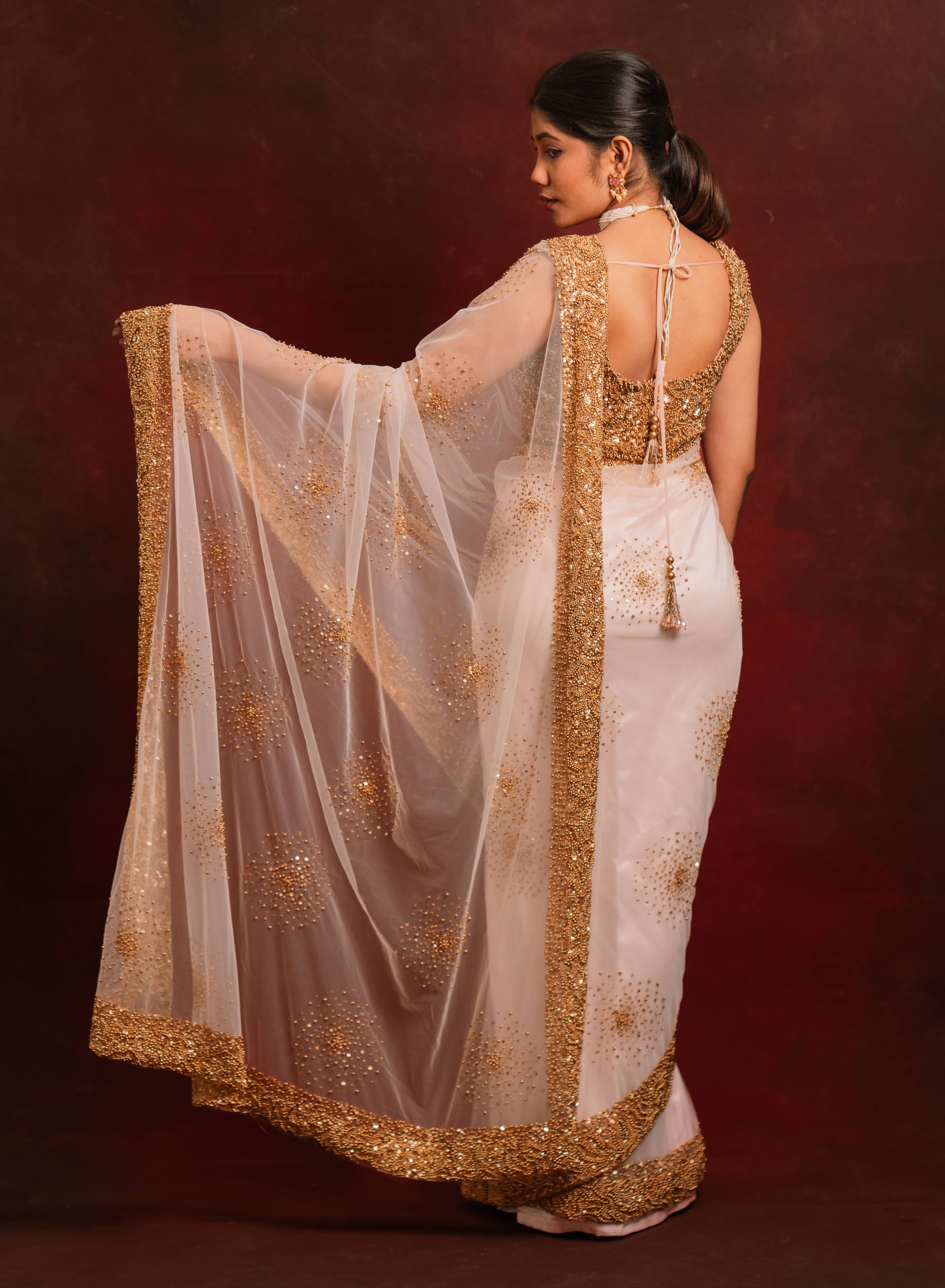 Back design details of ivory tulle saree intricately handcrafted with antique gold beads and sequins paired with a handcrafted blouse featuring similar work by team Archana Karthick