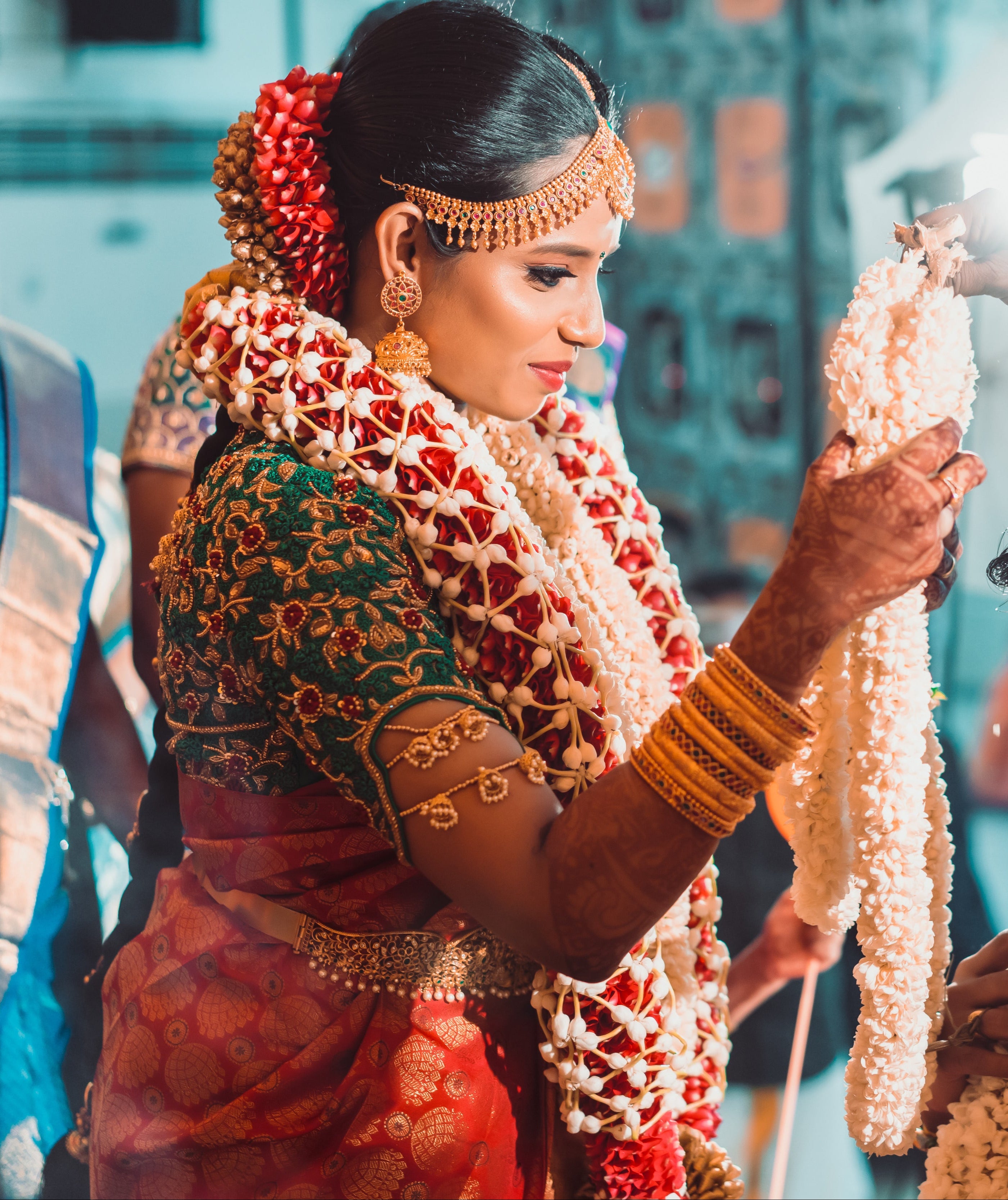Bride Abhinaya in a handcrafted green raw silk blouse designed by Archana Karthick. Posing with a garland.