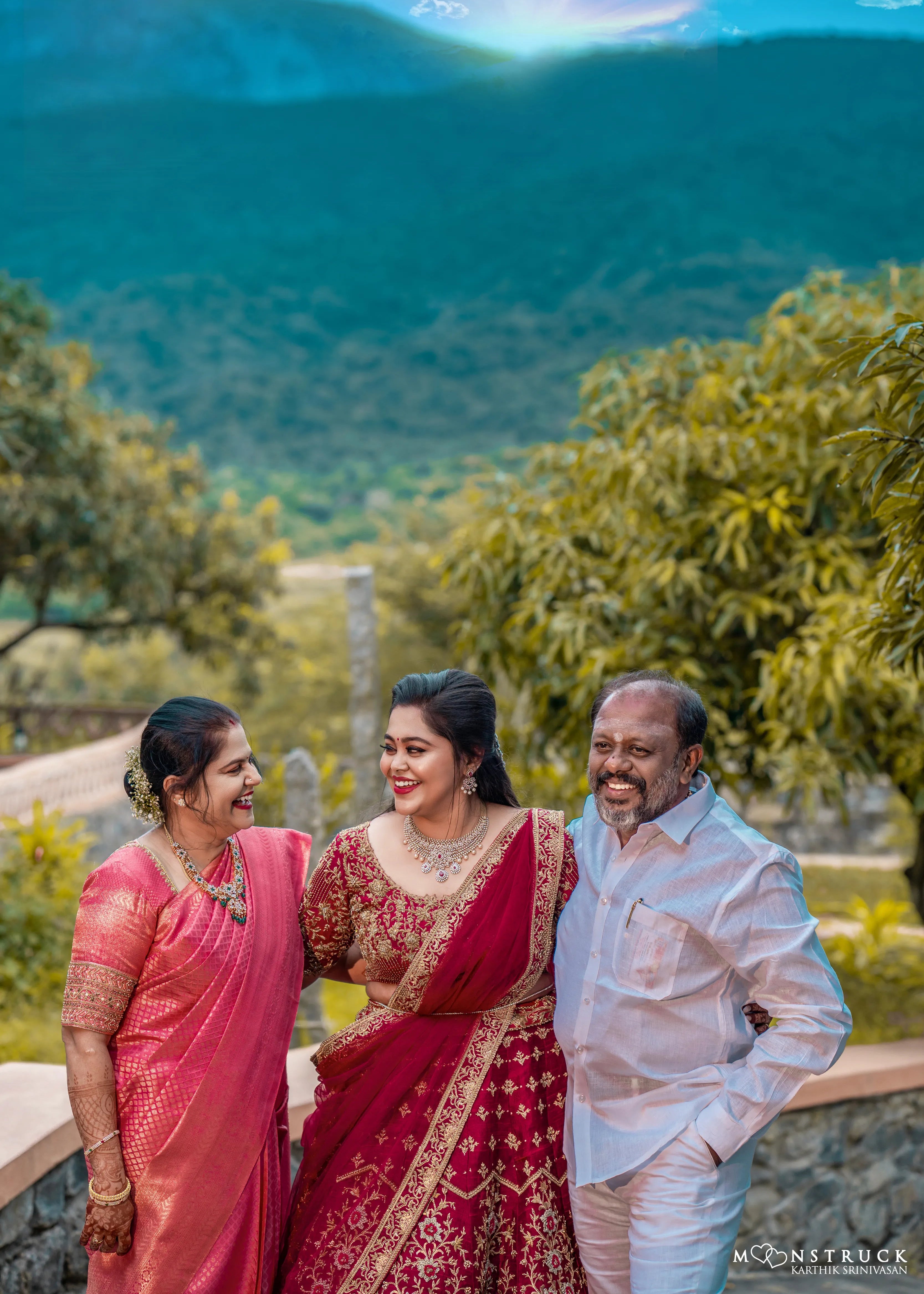 Bride Anjana from coimbatore posing with parents in a magenta red raw silk bridal lehenga designed by Archana Kartrhick.