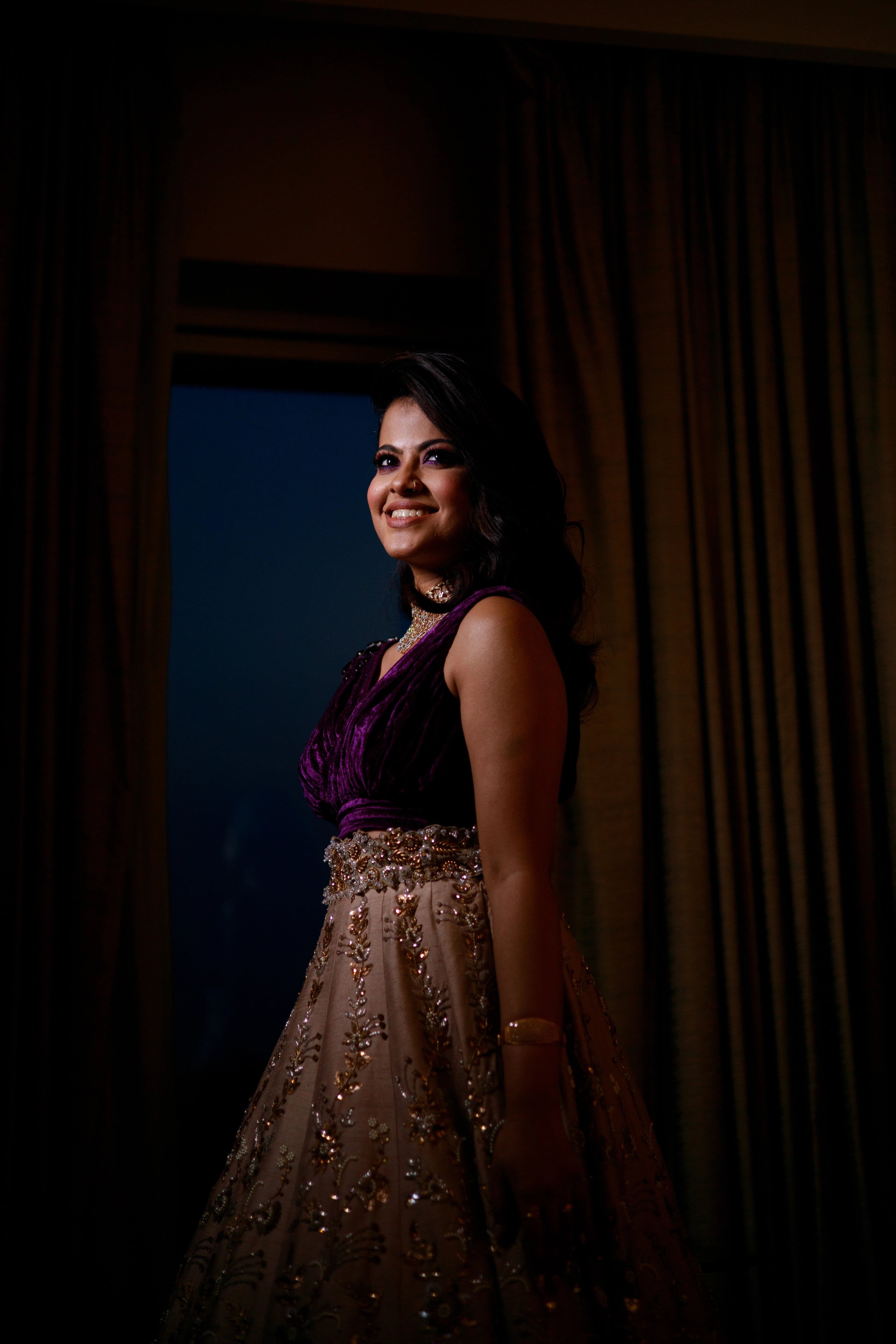 Bride Anu from Kerala smiling in a purple & beige lehenga, handcrafted by team Archana Karthick.