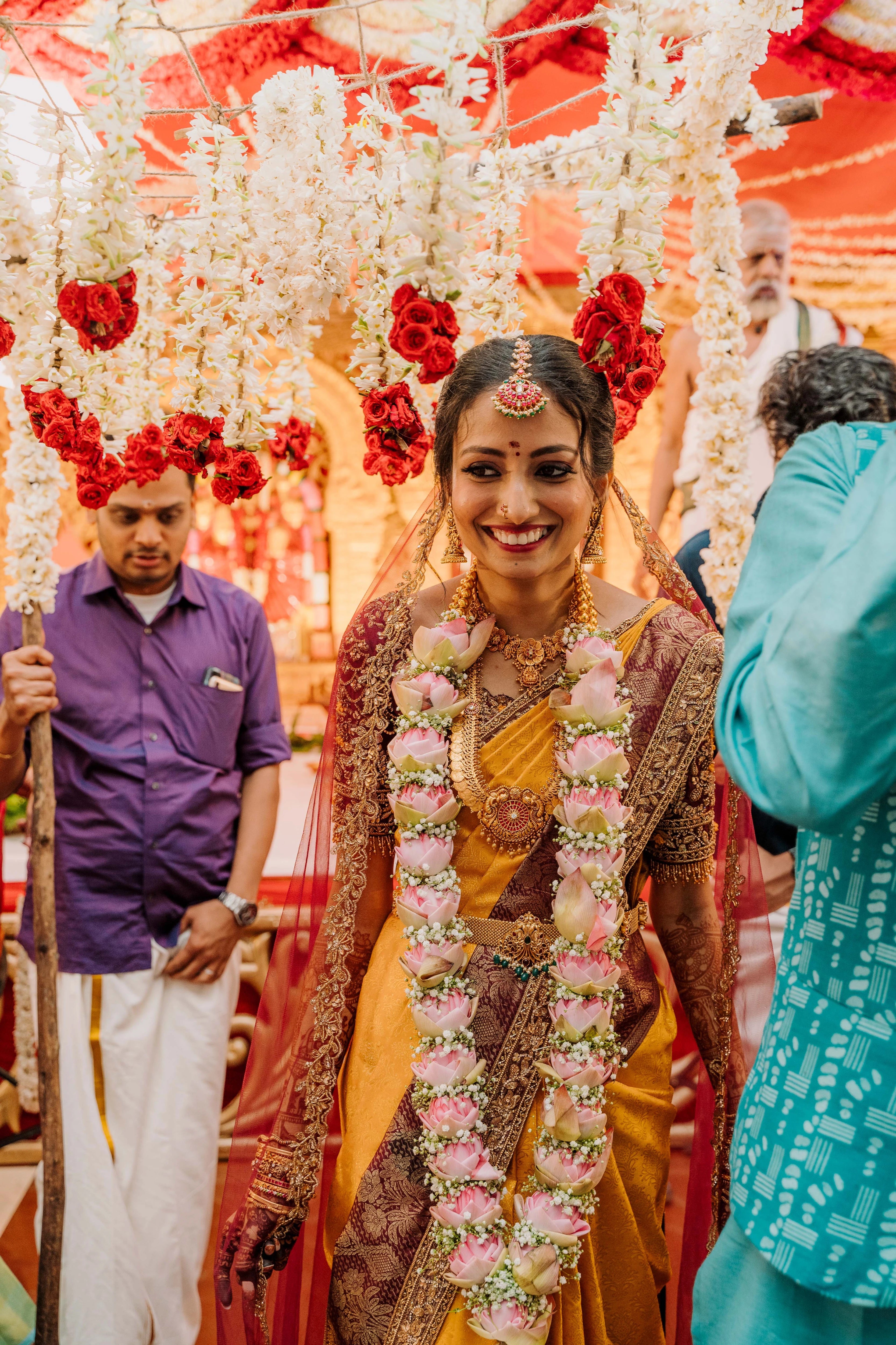 Bride Anusha K smiling in a wine red concept raw silk blouse, veil and saree border, handcrafted with zardosi, beads, resham, crystals, sequins etc by Archana Karthick.