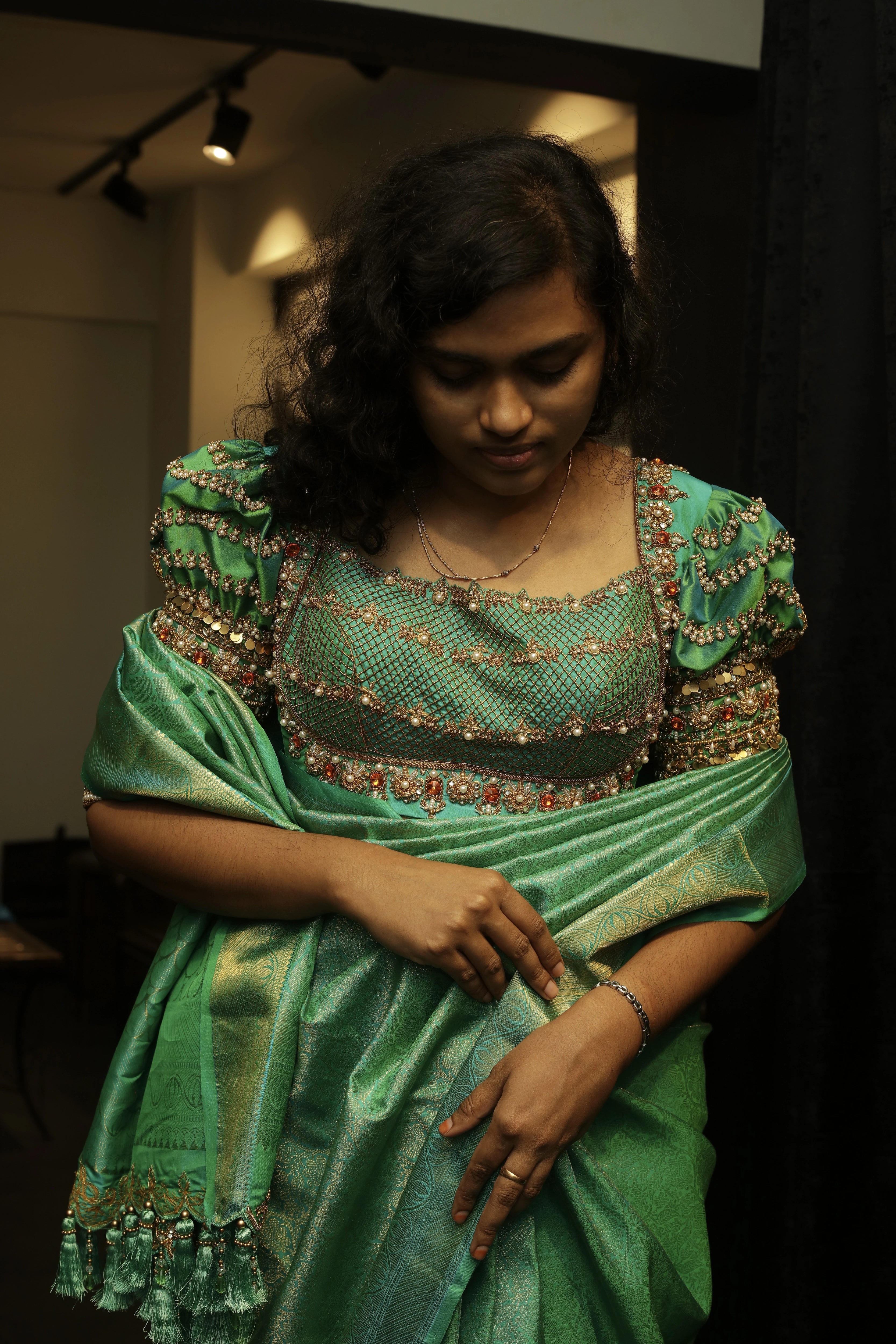 Bride Cris showcasing blouse front design in a sea green puff sleeved silk blouse & belt, tulle veil, handcrafted with appliques, beads, kundan, stones, crystals, etc by team Archana Karthick