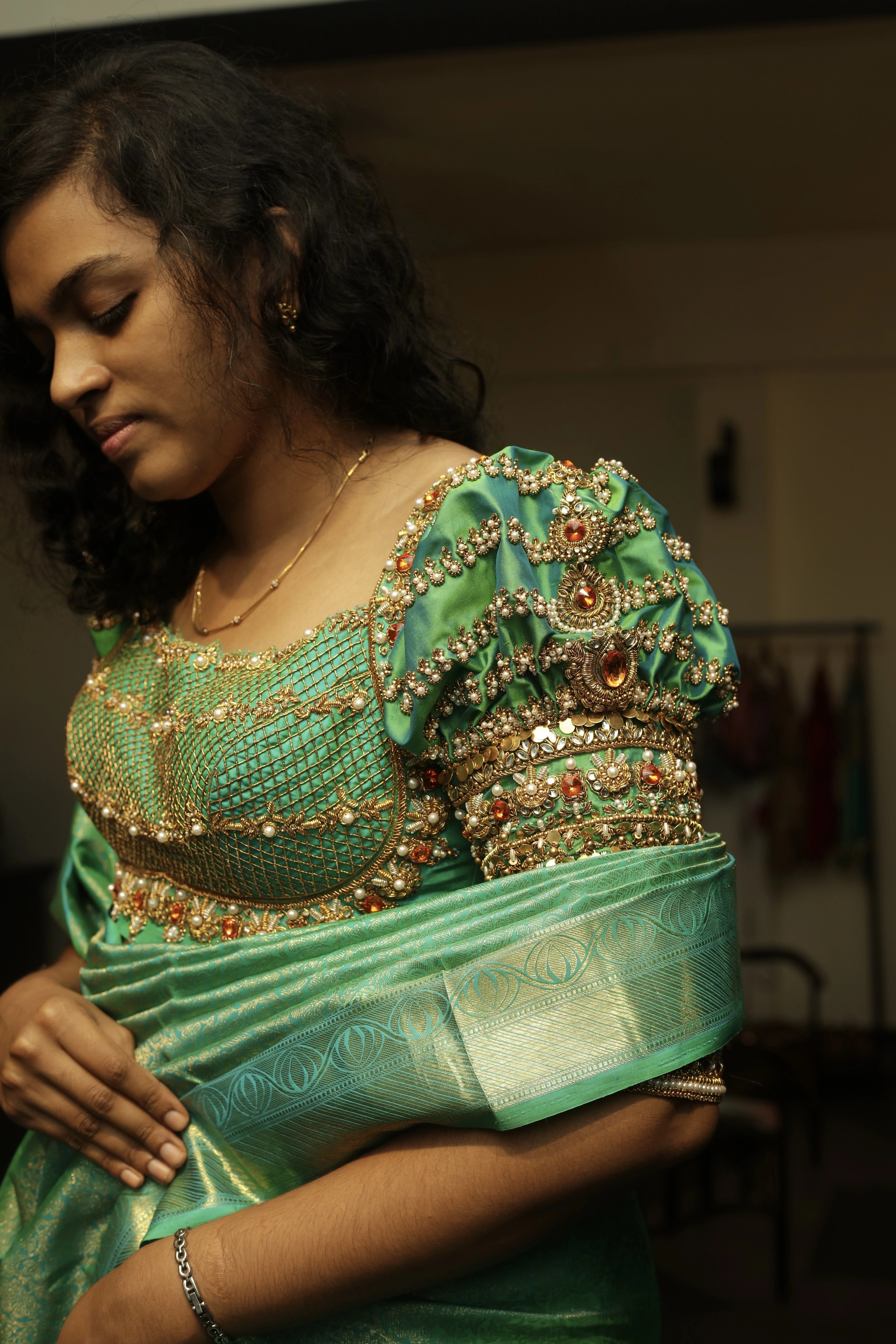 Bride Cris smiling in a sea green puff sleeved silk blouse & belt, tulle veil, handcrafted with appliques, beads, kundan, stones, crystals, etc by team Archana Karthick