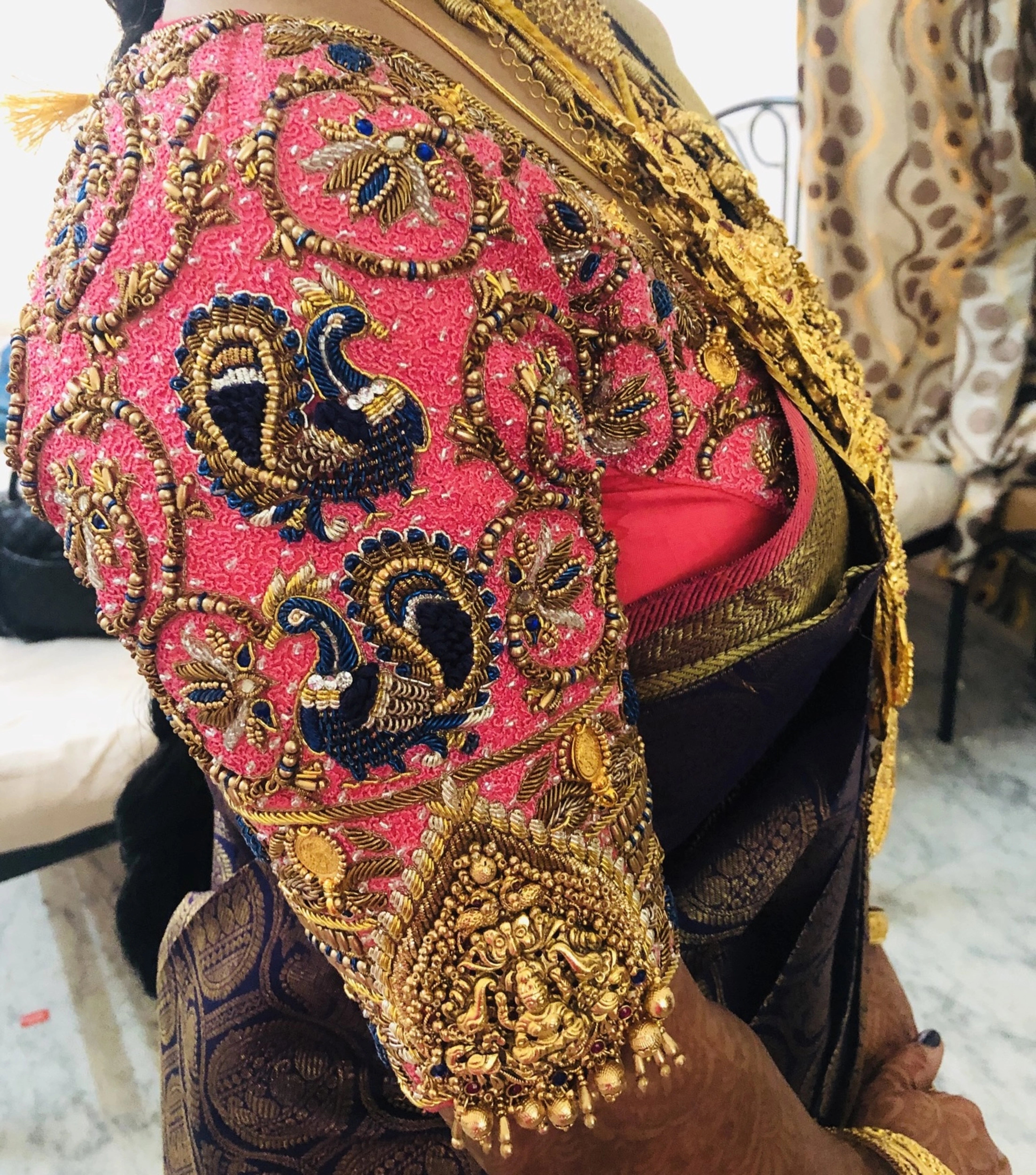 Bride Deepa showcasing blouse sleeves in a pink raw silk palanquin concept blouse, handcrafted with stones, resham, zardozi, sequins, beads, cutdana and jhumkas by team Archana Karthick.