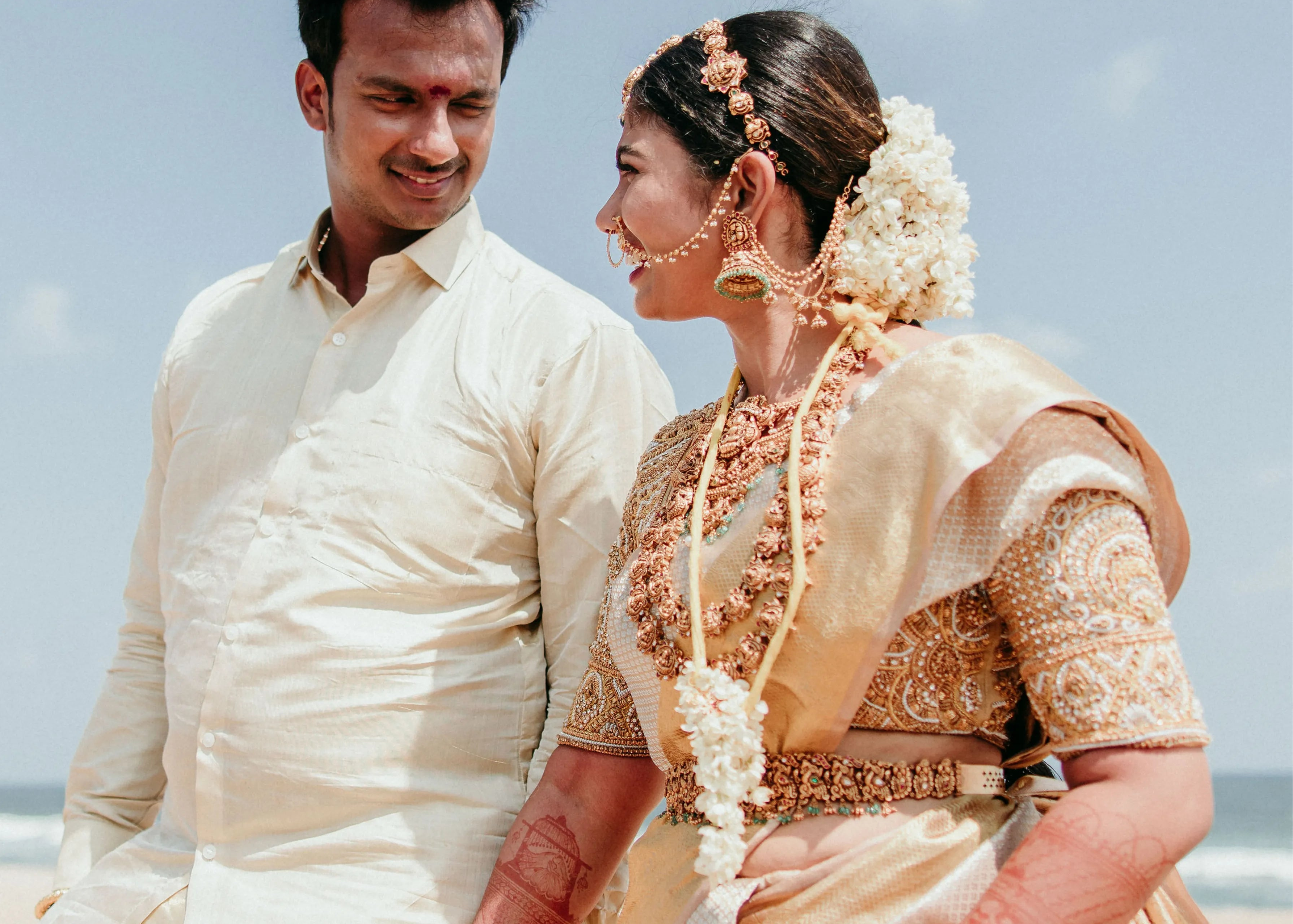 Bride Divya smiling in a gold silk blouse handcrafted by team Archana Karthick.