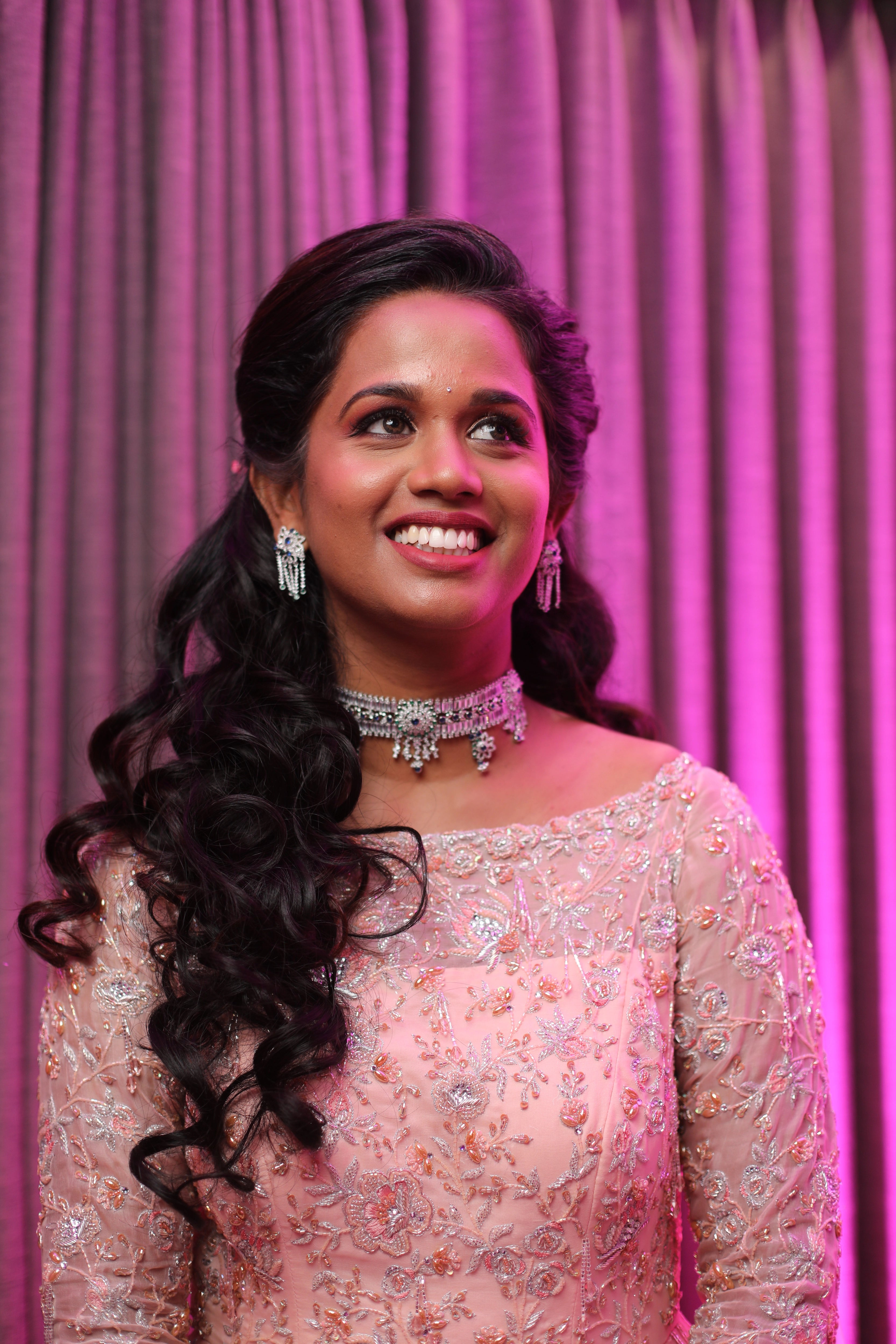Bride Gayathri looking happy in a peach cream tulle gown, handcrafted with applique work, stones, sequins, zari, cutdana and resham by team Archana Karthick.