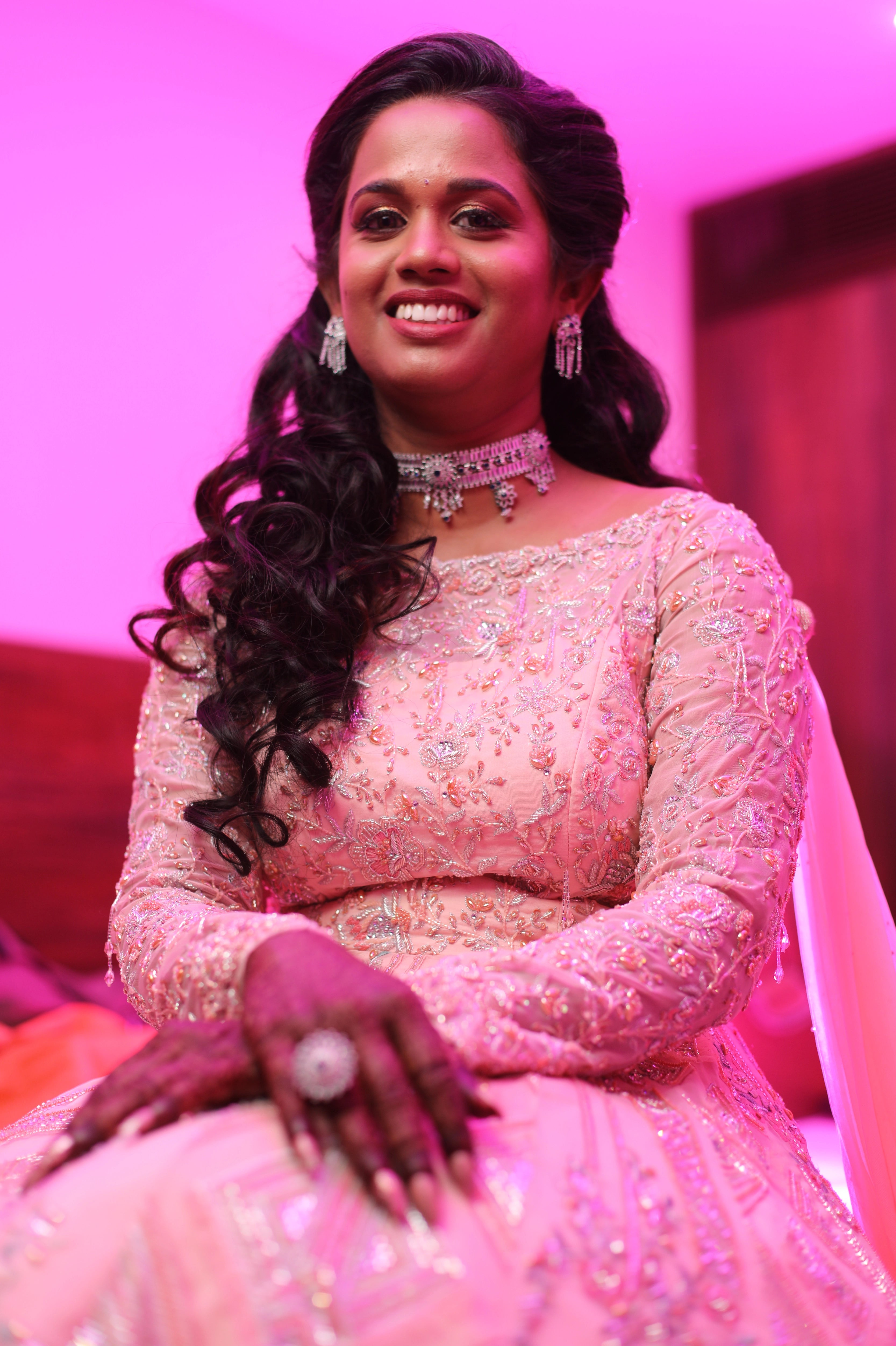 Bride Gayathri smiling at the lens in a peach cream tulle gown, handcrafted with applique work, stones, sequins, zari, cutdana and resham by team Archana Karthick.