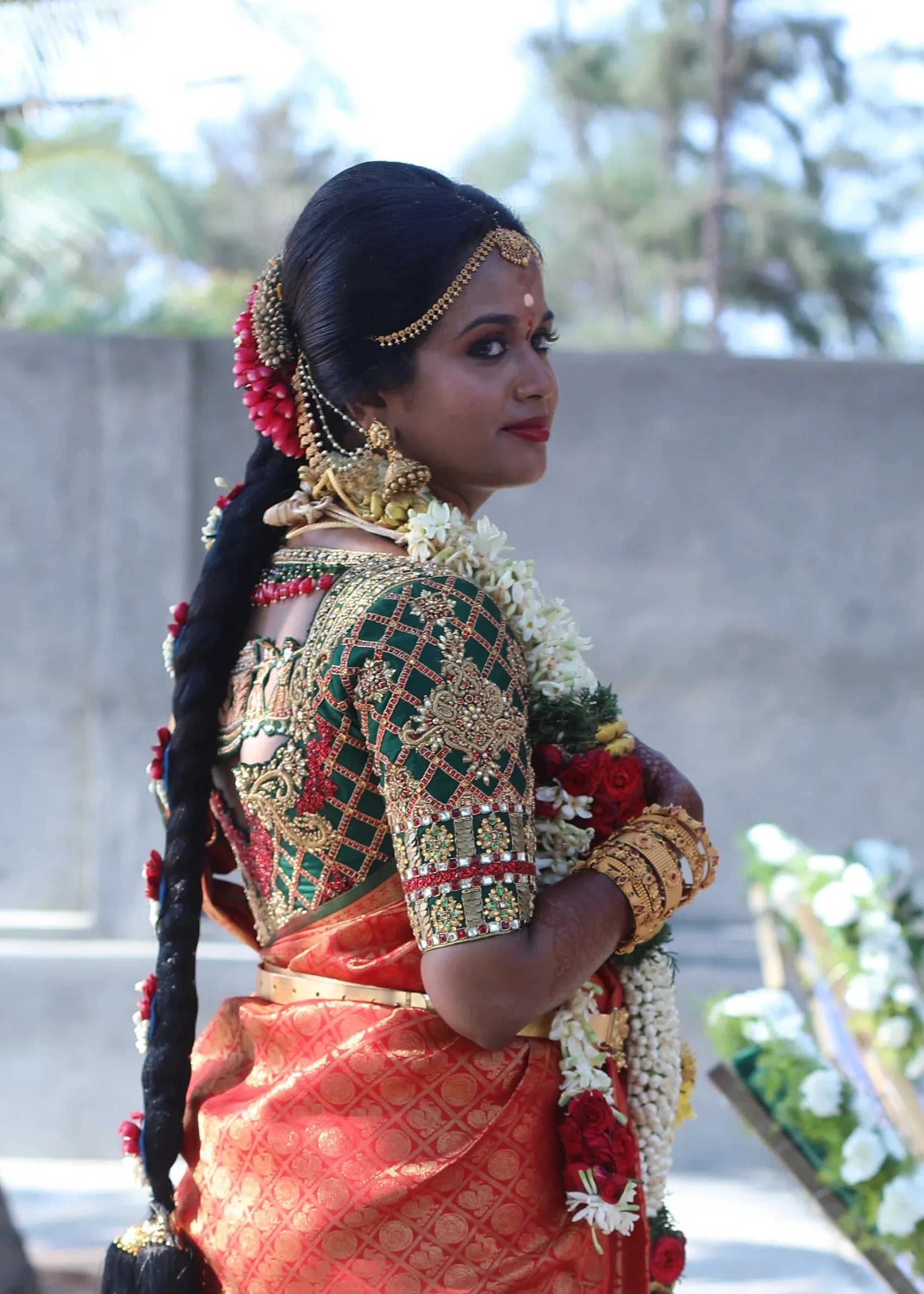 Bride Gayathri smiling in a palanquin concept bottle green silk blouse, handcrafted with kemp stones, zardozi, coins and crystals by team Archana Karthick.