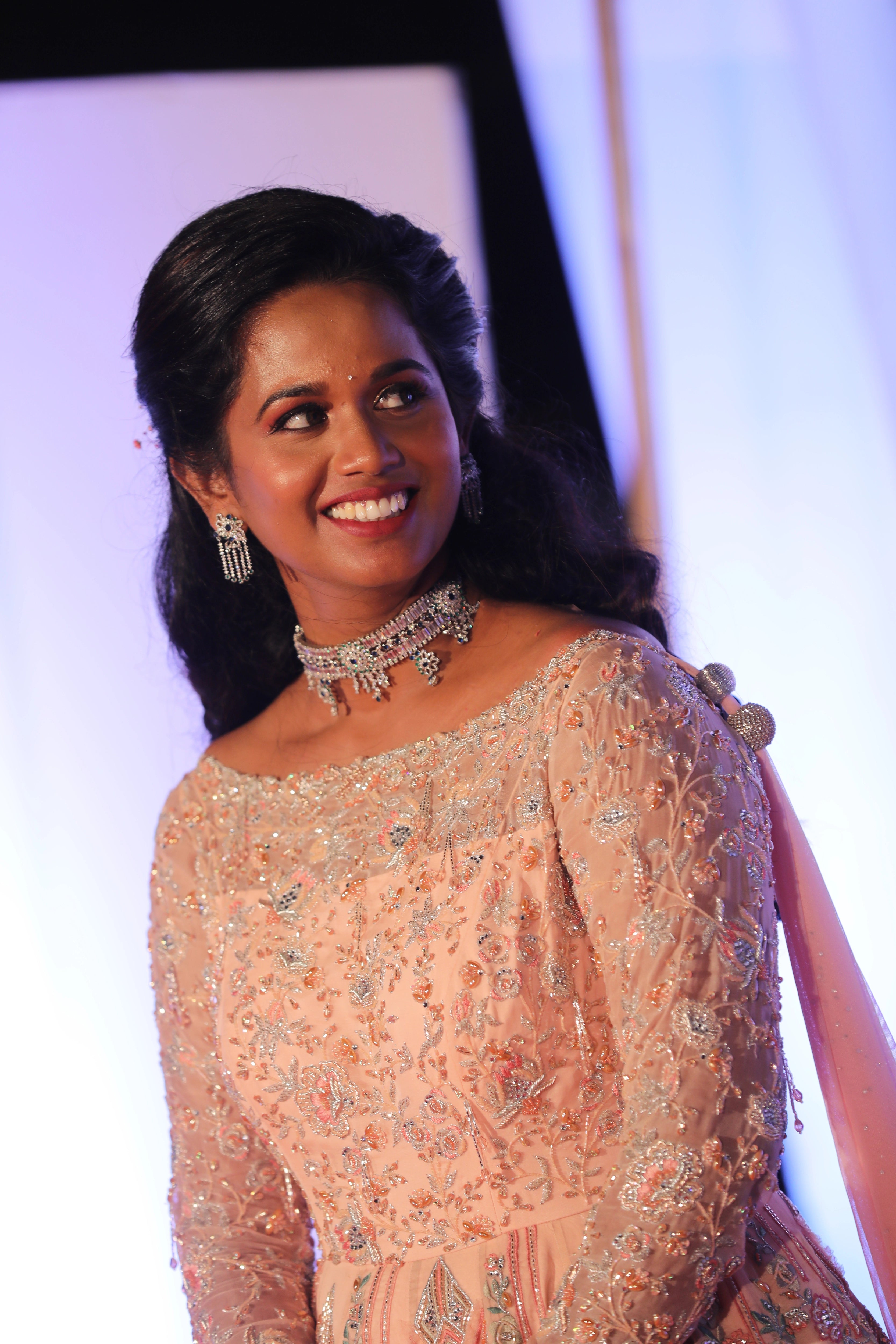 Bride Gayathri smiling in a peach cream tulle gown, handcrafted with applique work, stones, sequins, zari, cutdana and resham by team Archana Karthick.