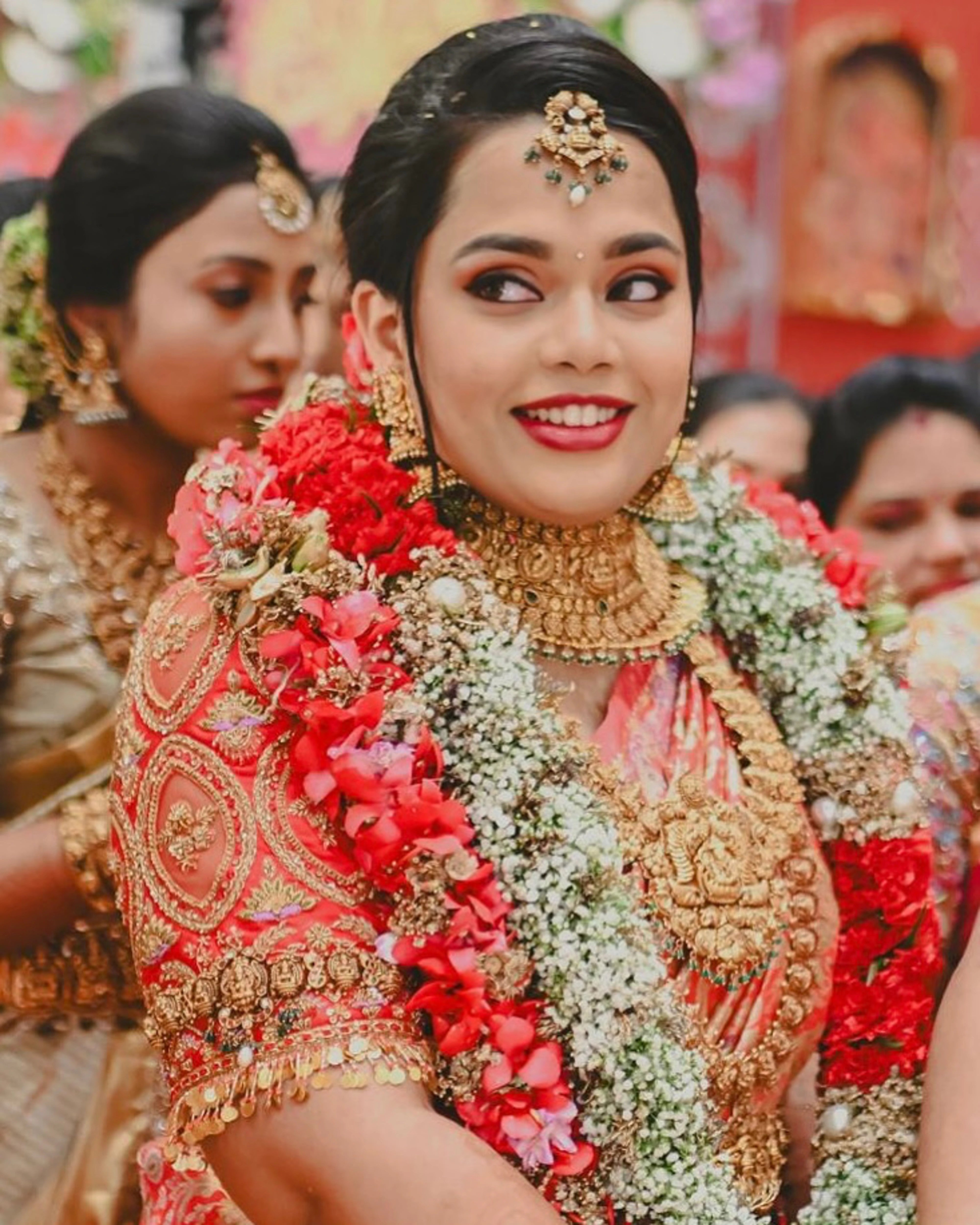 Bride Gayathri smiling in a red silk blouse by team Archana Karthick.