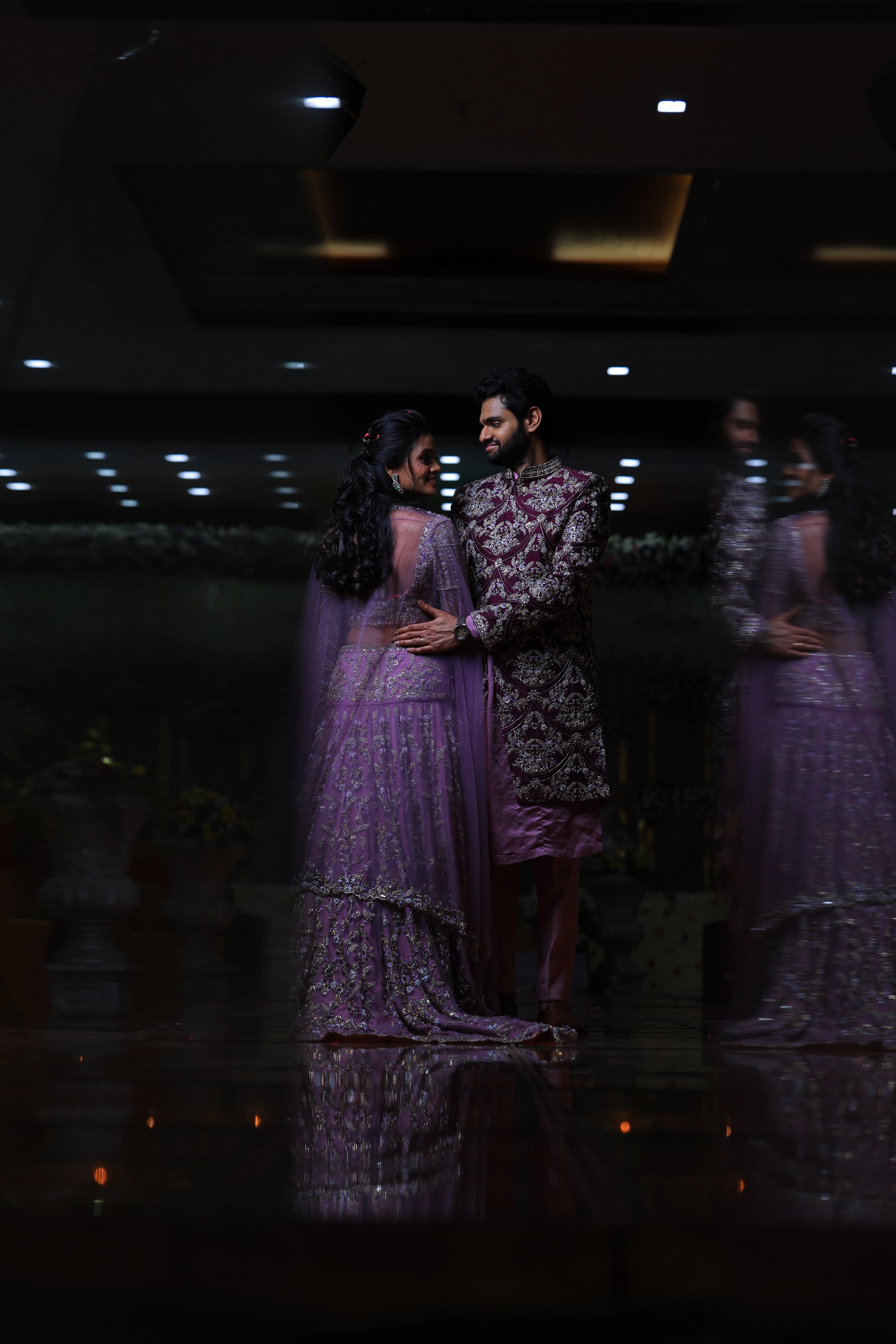 Bride & Groom in an embrace in lavender raw silk lehenga and sherwani, handcrafted with sequins, cutdana, beads, crystals, rhinestones and zardozi by Archana Karthick