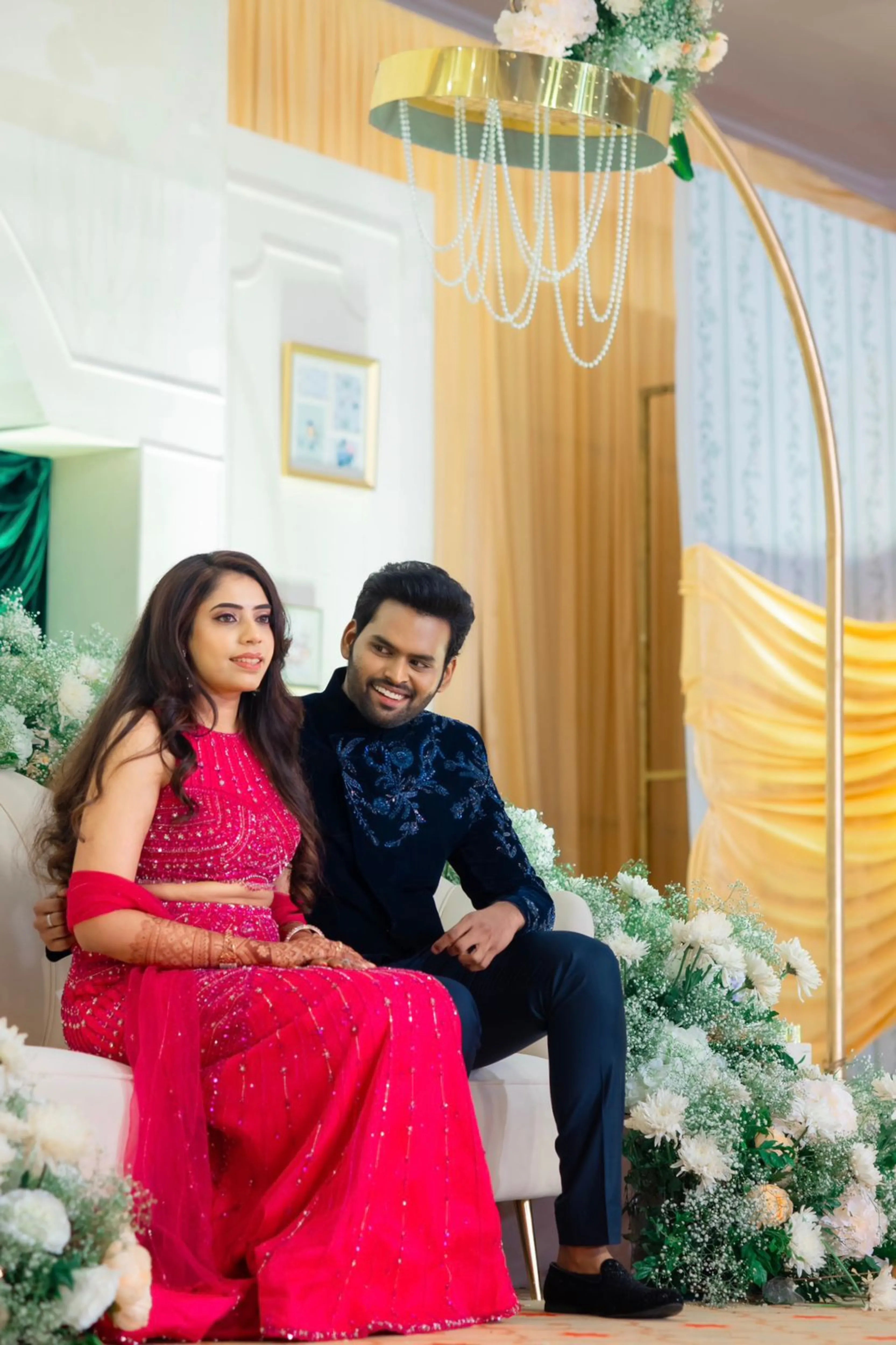 Bride & Groom posing in a pink tulle mermaid lehenga and midnight blue velvet bandhgala, intricately handcrafted by team Archana Karthick